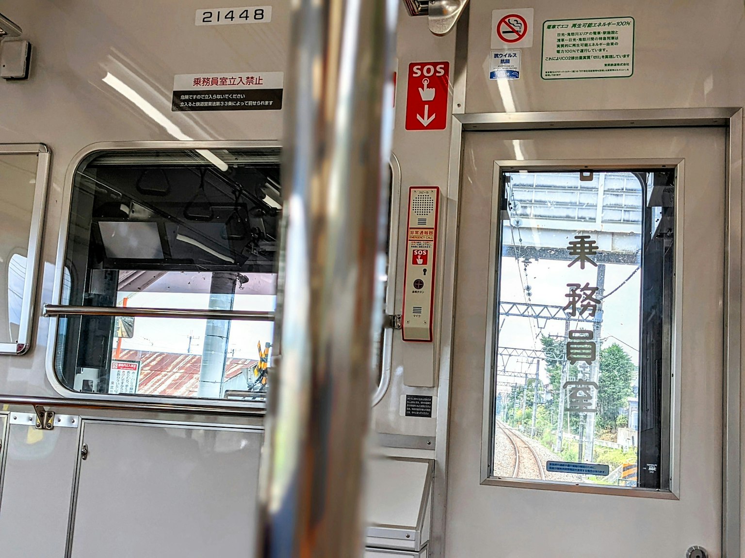 Vue intérieure d'un train montrant une fenêtre et une rampe métallique avec un paysage extérieur