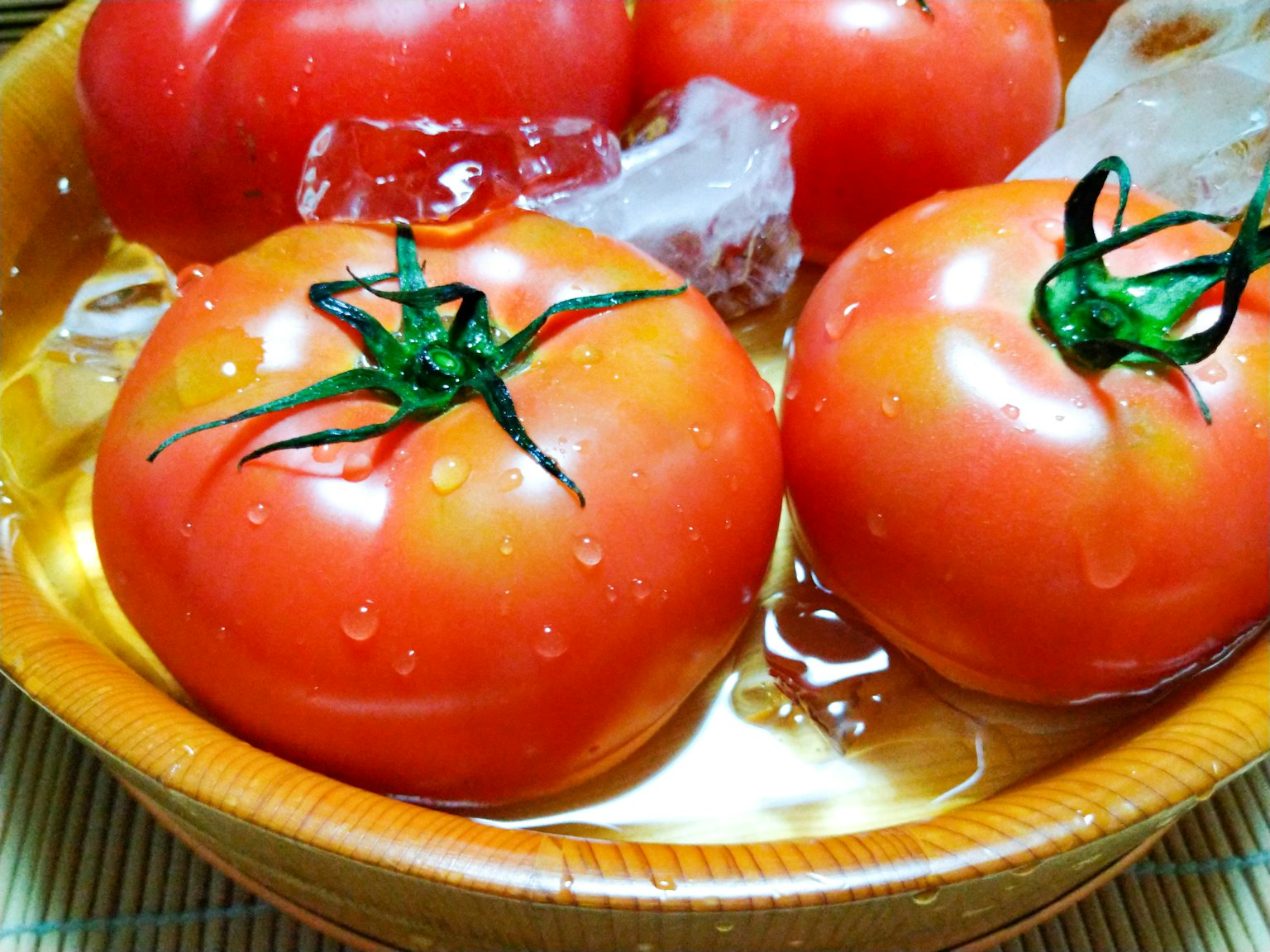 Fresh tomatoes immersed in ice water in a wooden bowl