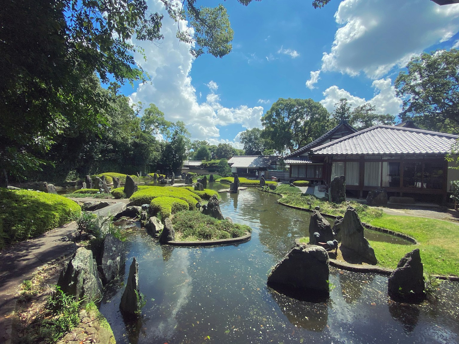 Paysage de jardin japonais serein avec une verdure luxuriante et un étang avec un bâtiment traditionnel