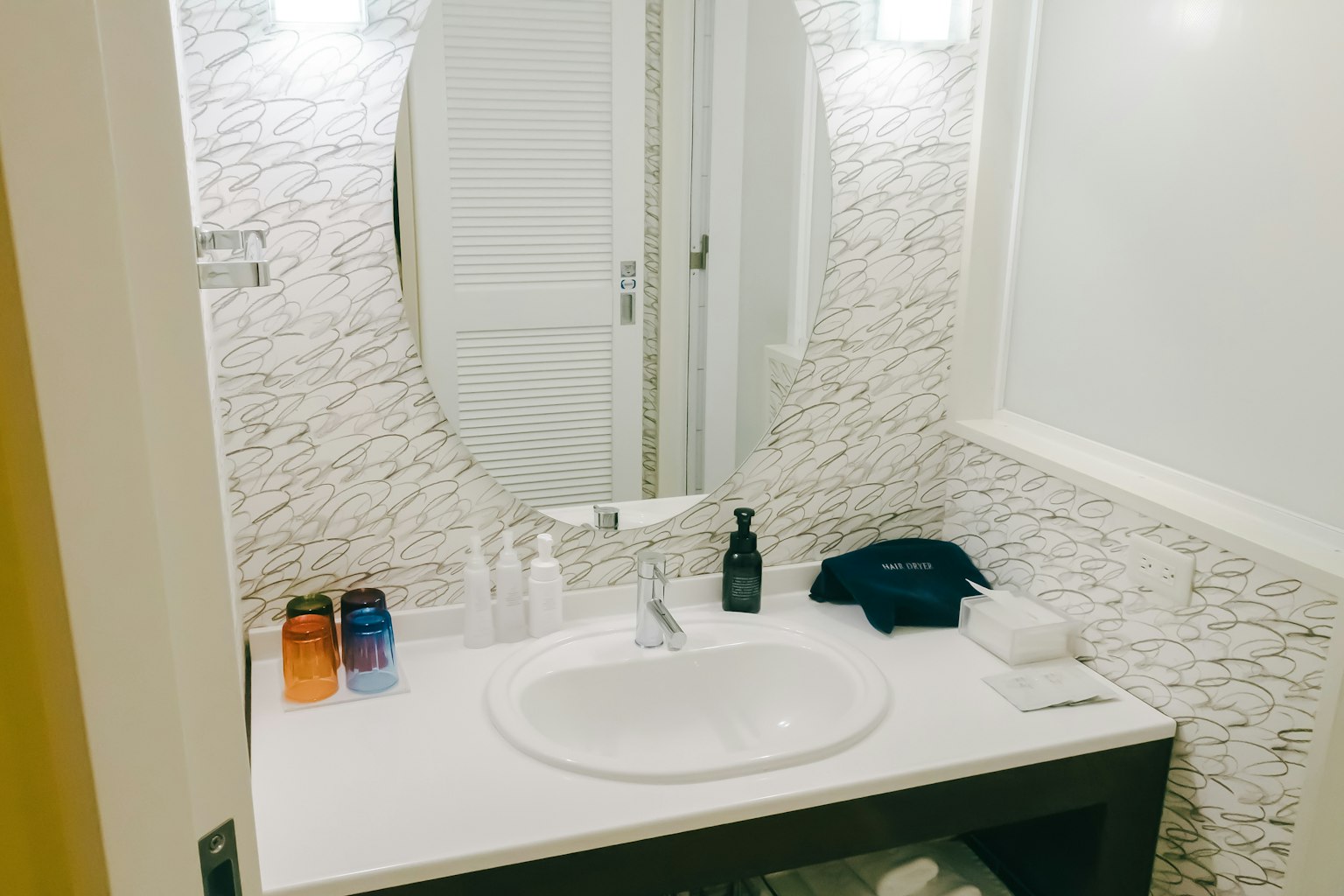 Moderne Badezimmeransicht mit Waschbecken und Spiegel mit bunten Flaschen