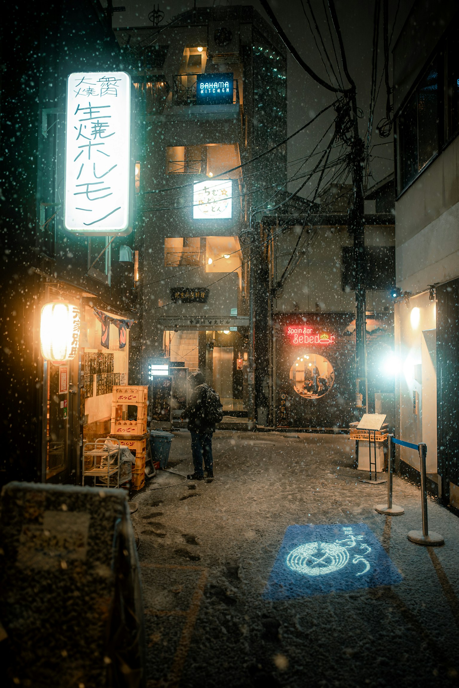 在下雪的東京小巷中站著的人和霓虹燈