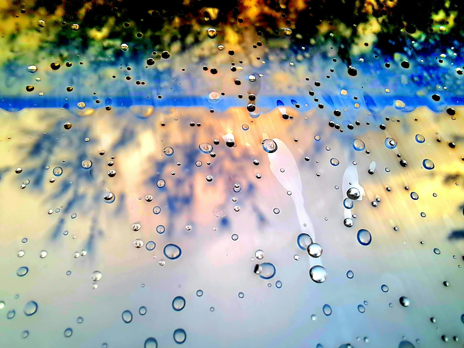 Paesaggio colorato e riflessi visti attraverso una finestra con gocce di pioggia