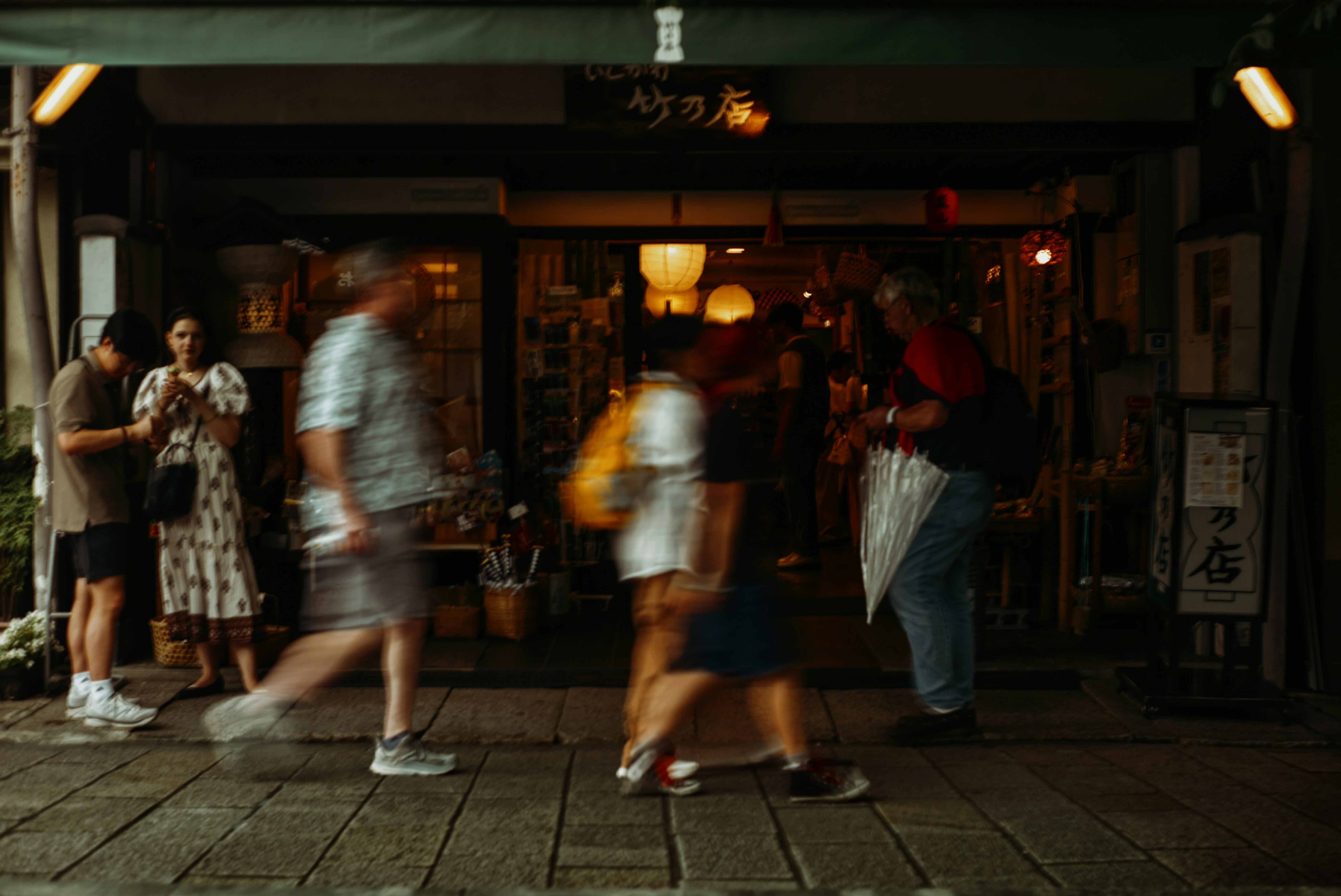 Gasse in der Einkaufsstraße von Arashiyama mit vorbeigehenden Menschen und Laternenlicht