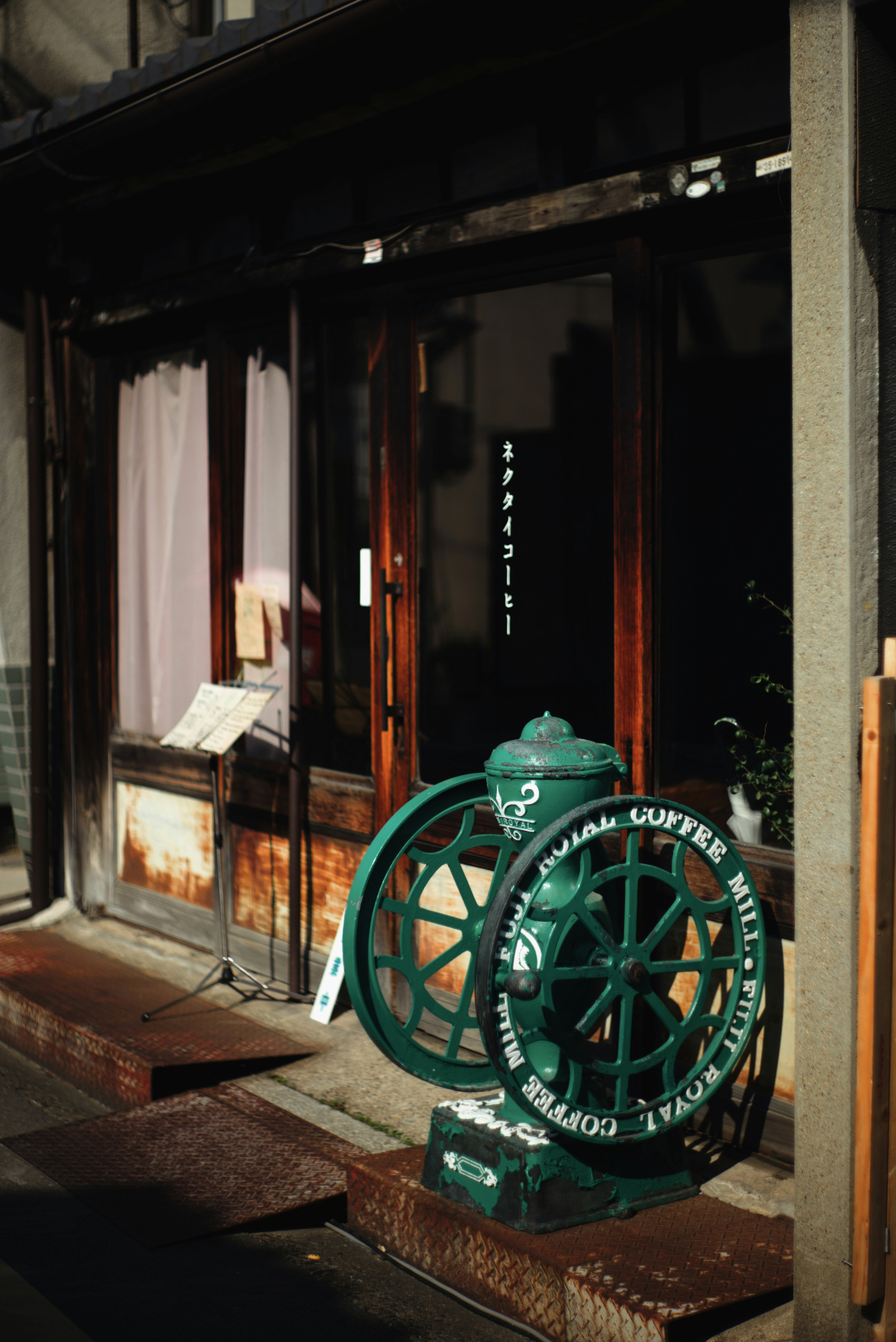 路地の店先に置かれたレトロなコーヒー焙煎機と看板