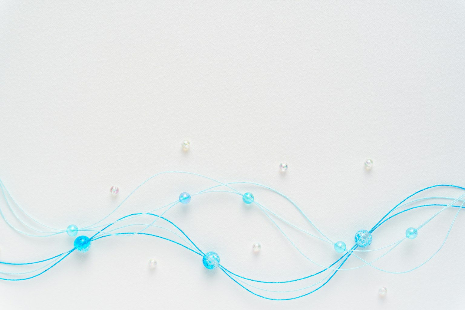 Un fond simple avec des fils bleus et des perles disposées en motif ondulant