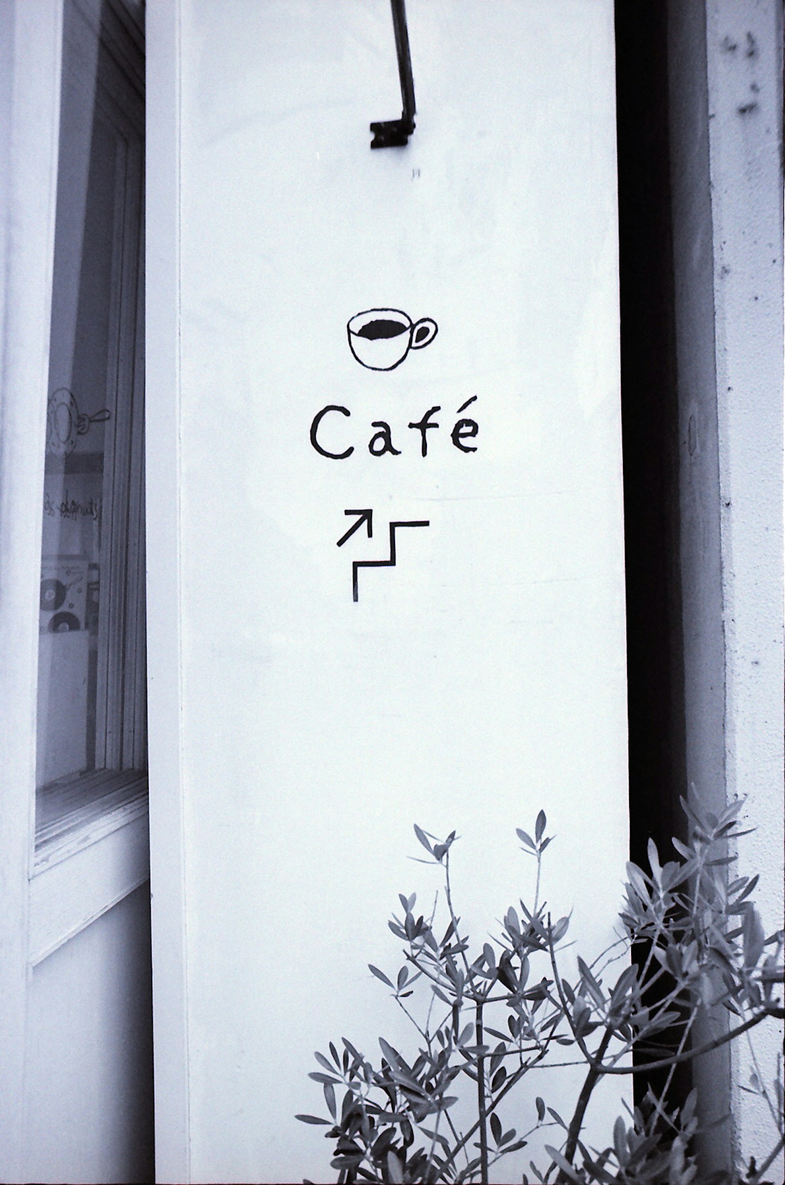 White wall with a café sign featuring a coffee cup and arrow