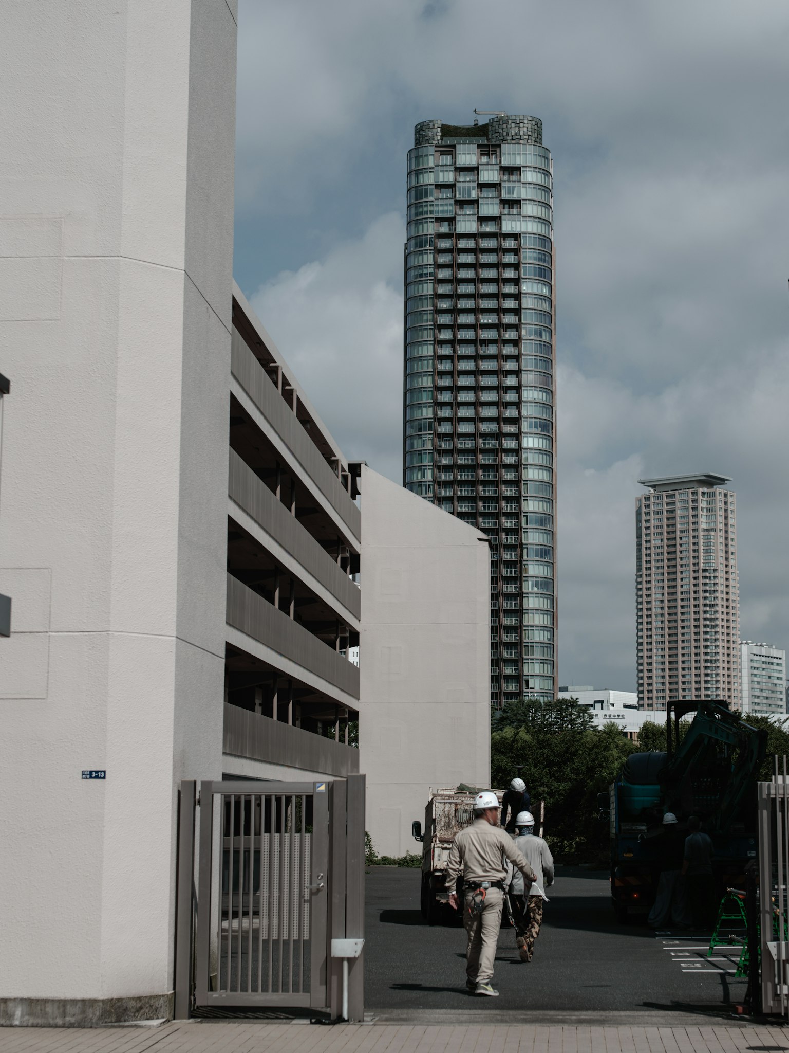 มุมมองของอาคารสูงและโครงสร้างที่จอดรถพร้อมคนเดิน