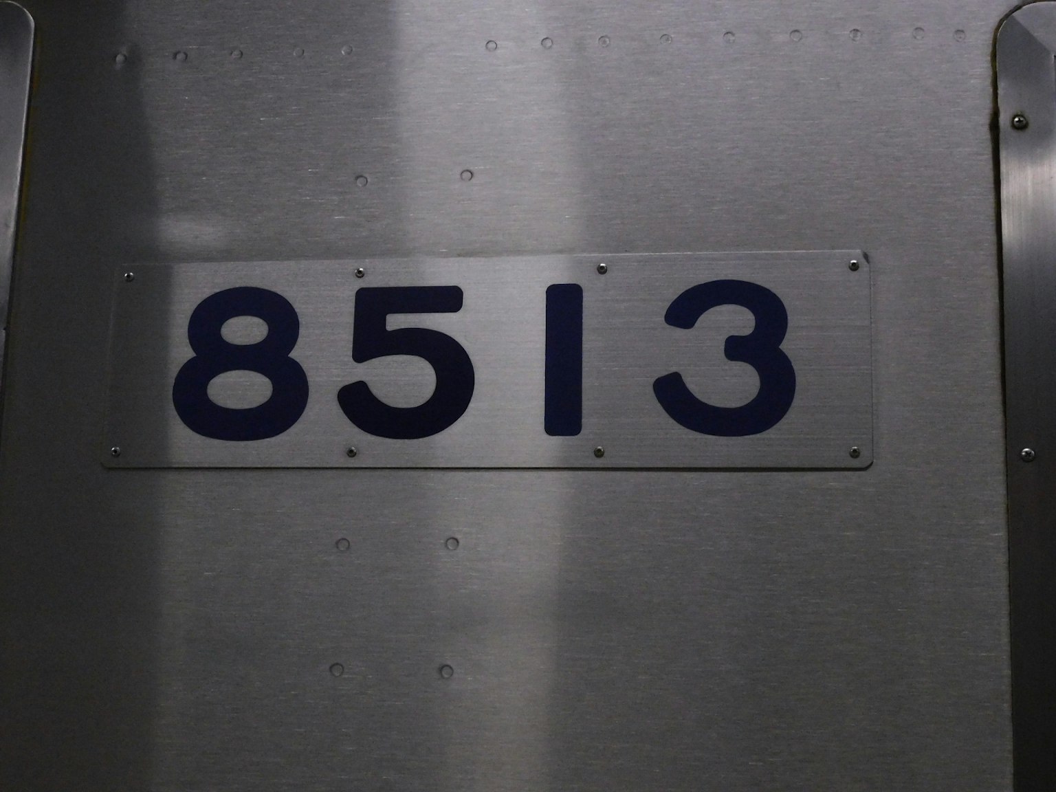 Large number 8513 displayed on a silver metal surface