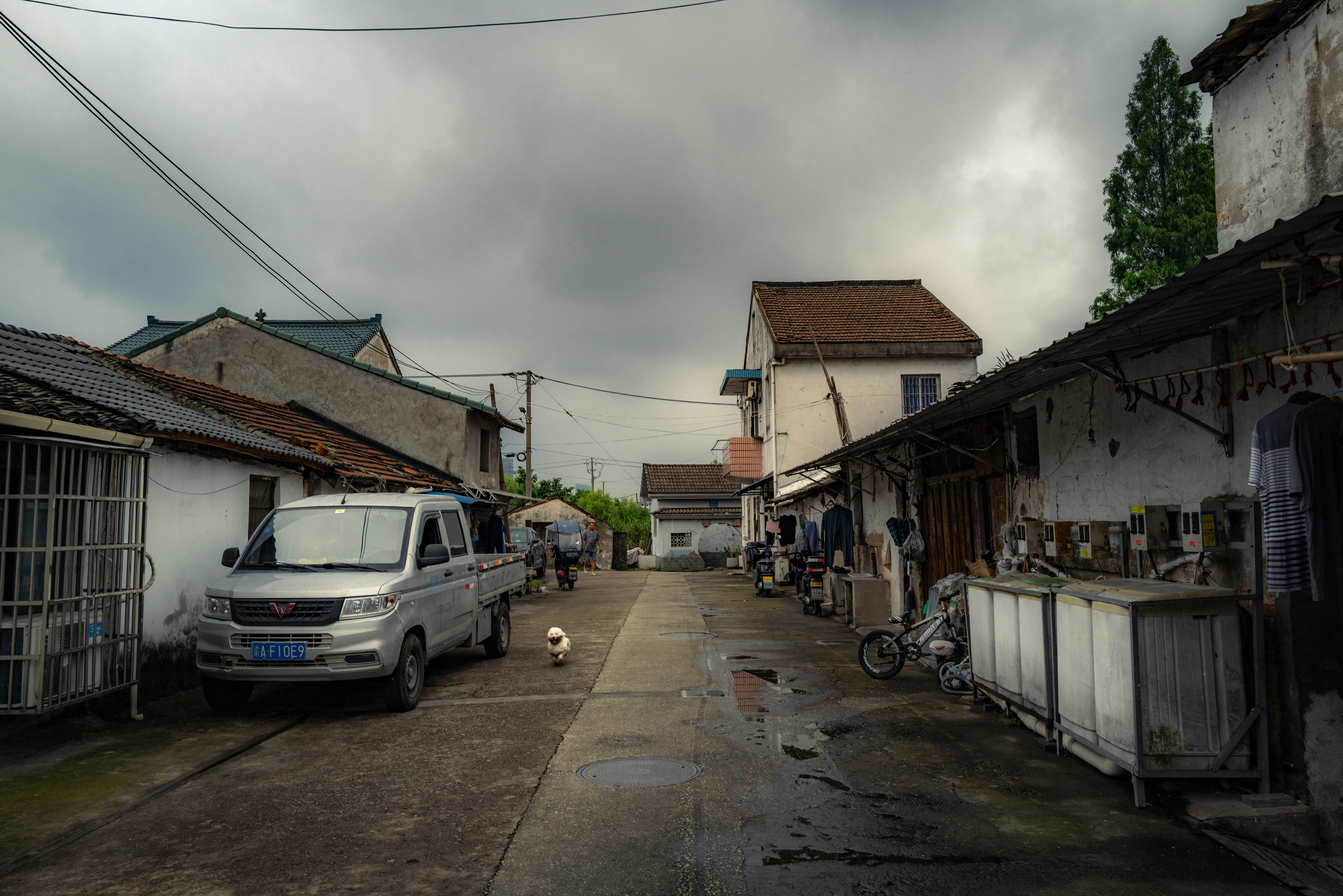 路地に並ぶ車と自転車のある住宅街の軒先