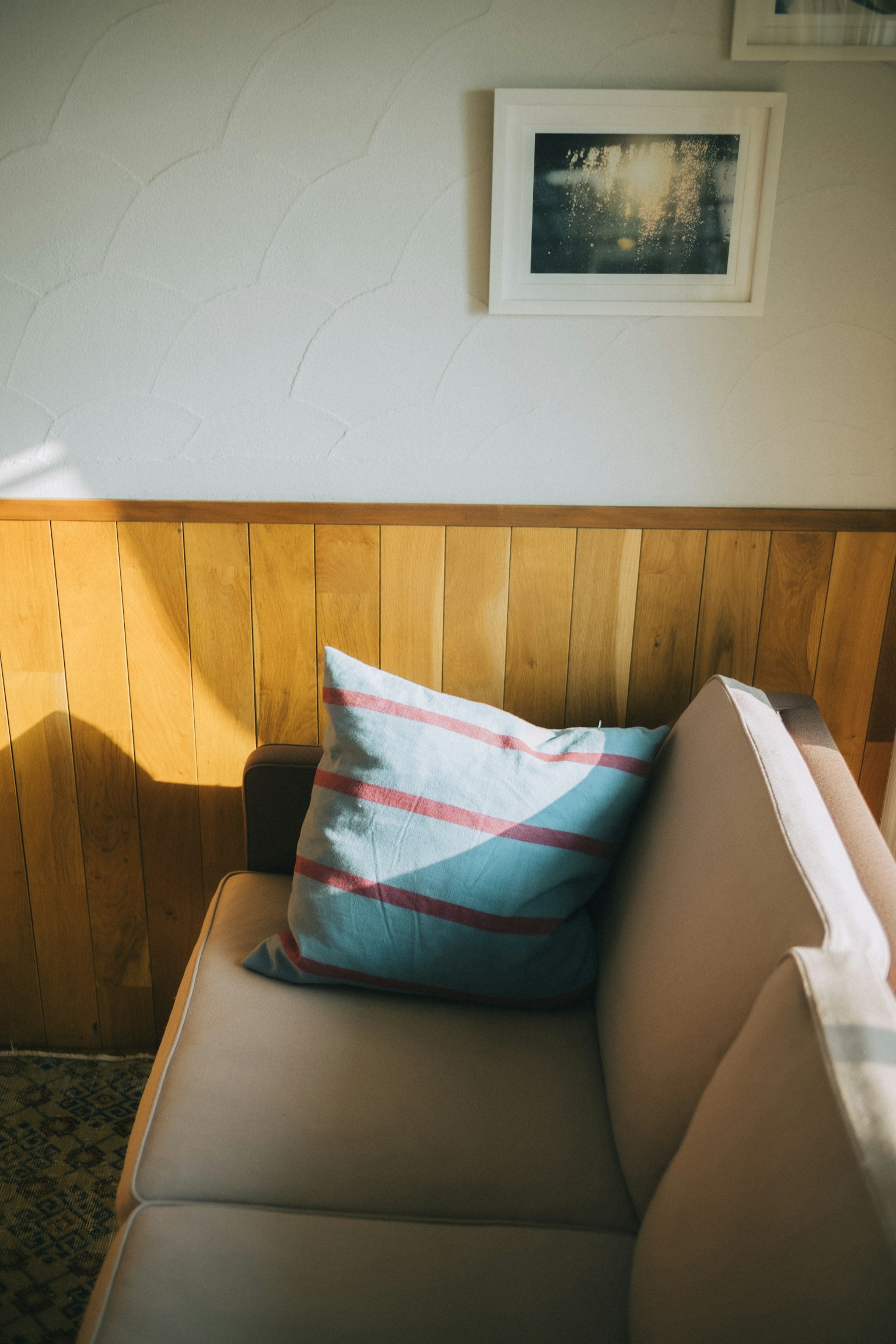 Une section d'un canapé avec un coussin coloré et un mur en bois