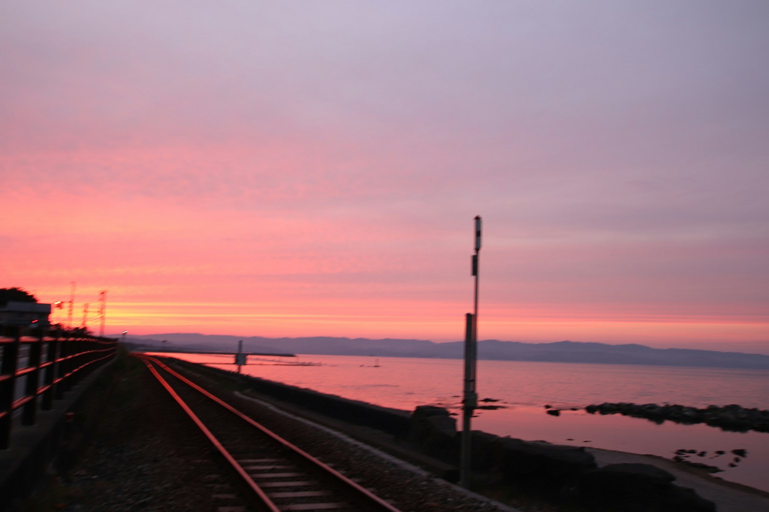 Atardecer sobre el mar con vías de tren