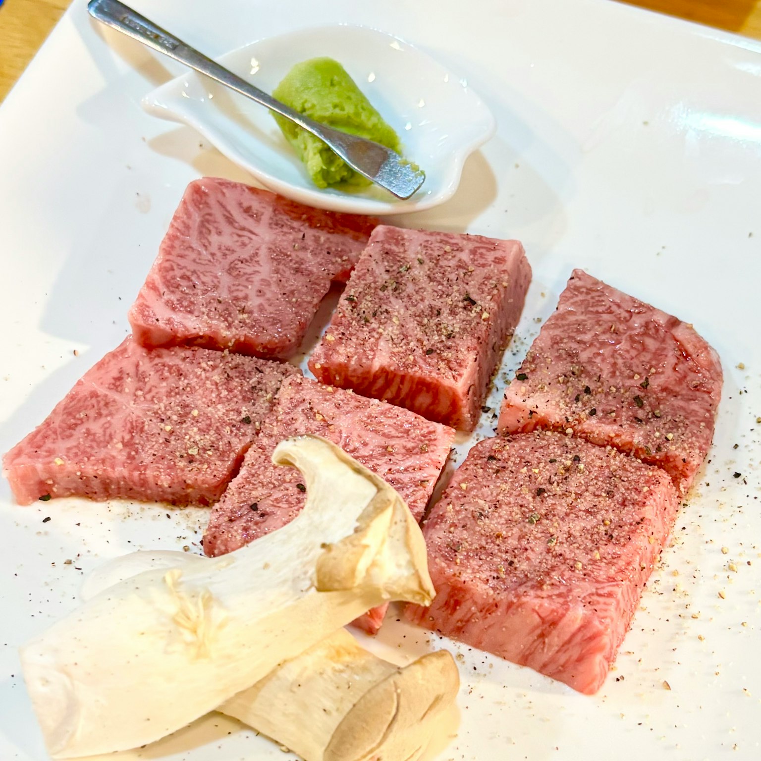 Cubetti di manzo Wagyu freschi serviti su un piatto con wasabi e funghi