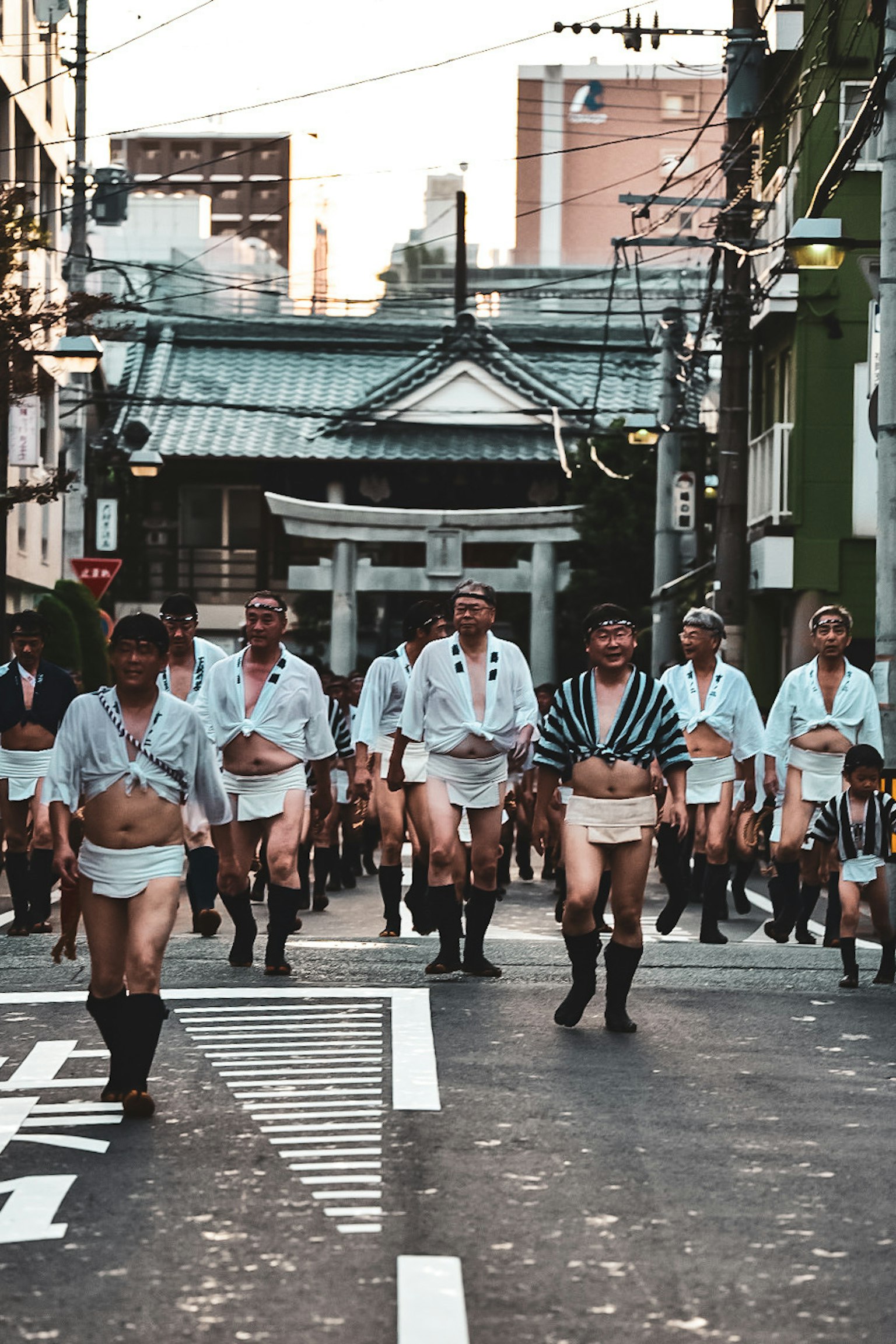 Hombres corriendo en trajes tradicionales durante una escena de festival con un santuario al fondo