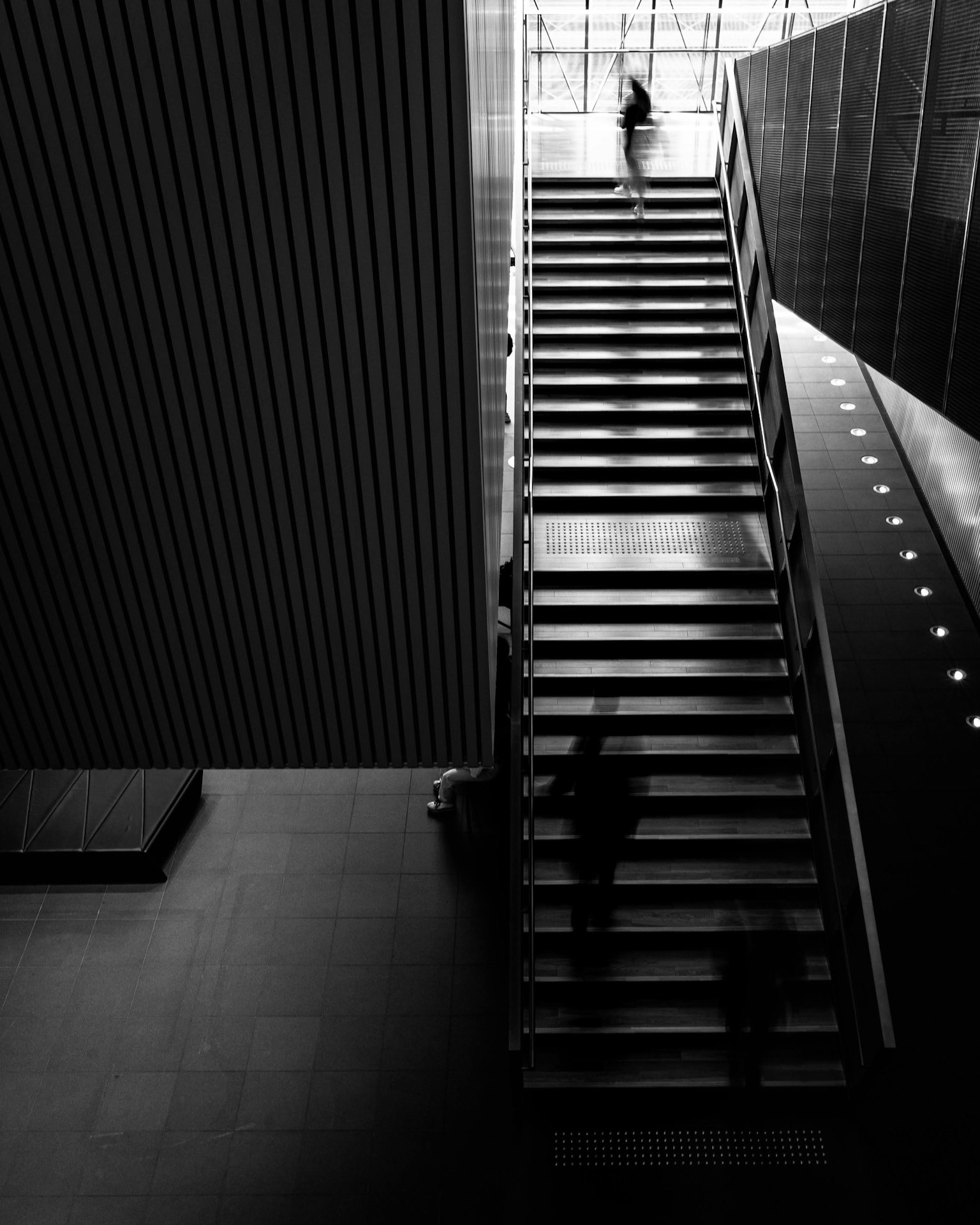 Silhouette di una persona che sale una scala in bianco e nero in un interno di architettura moderna