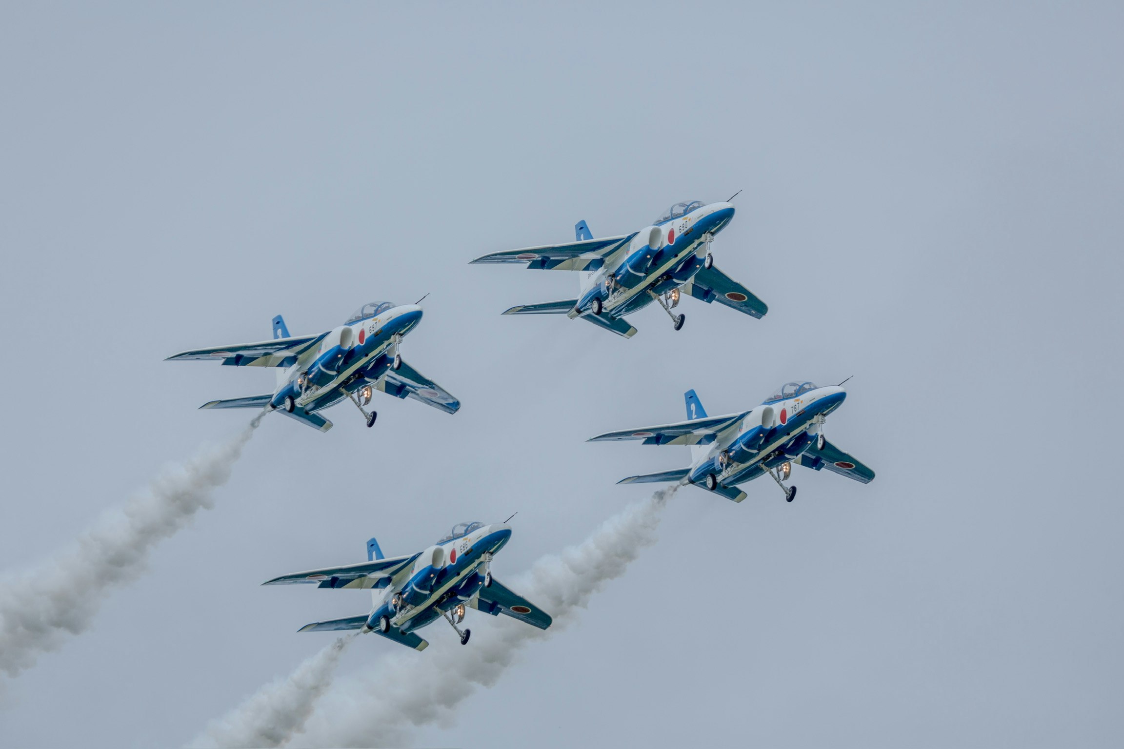 Blaue Jet-Flugzeuge im Formationsflug mit weißen Rauchschwaden