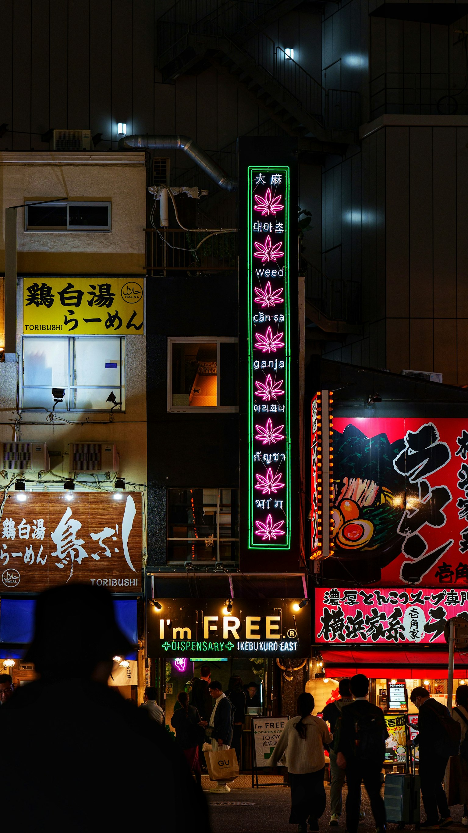 夜の街並みにある明るい看板と人々のシルエット