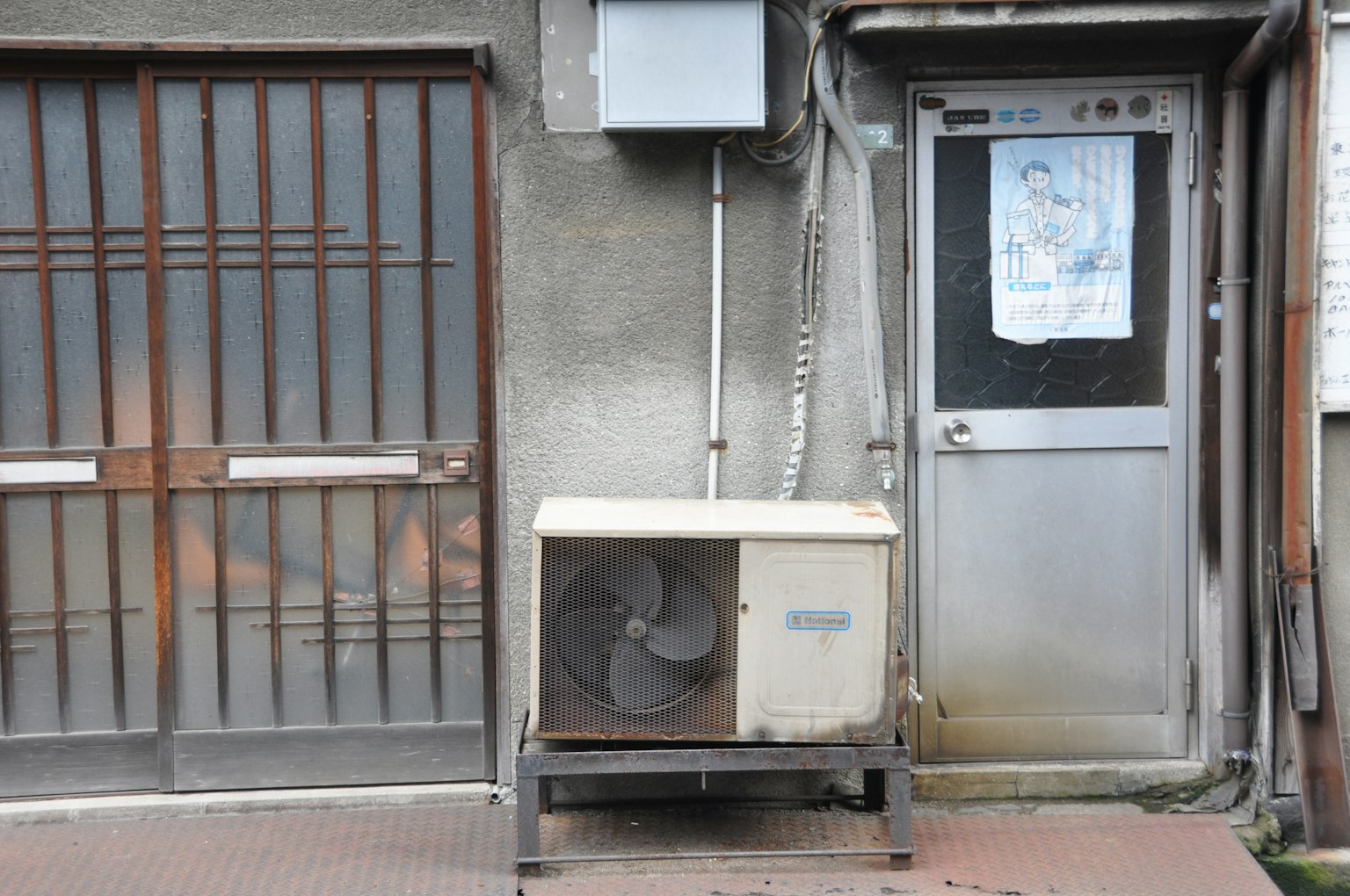 Unità di climatizzazione accanto a un vecchio edificio con porta in metallo