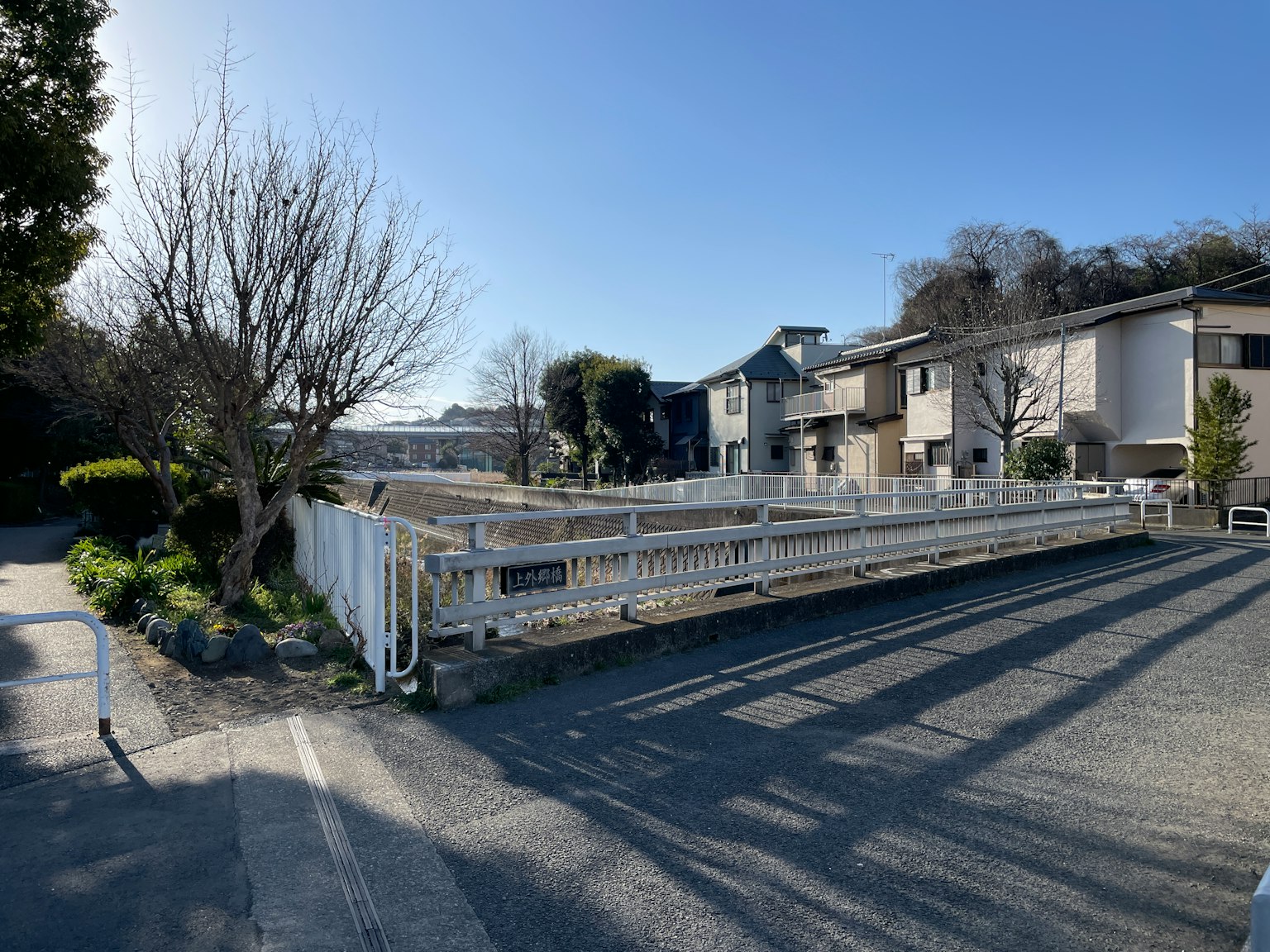 A view of a residential area featuring a white fence and trees