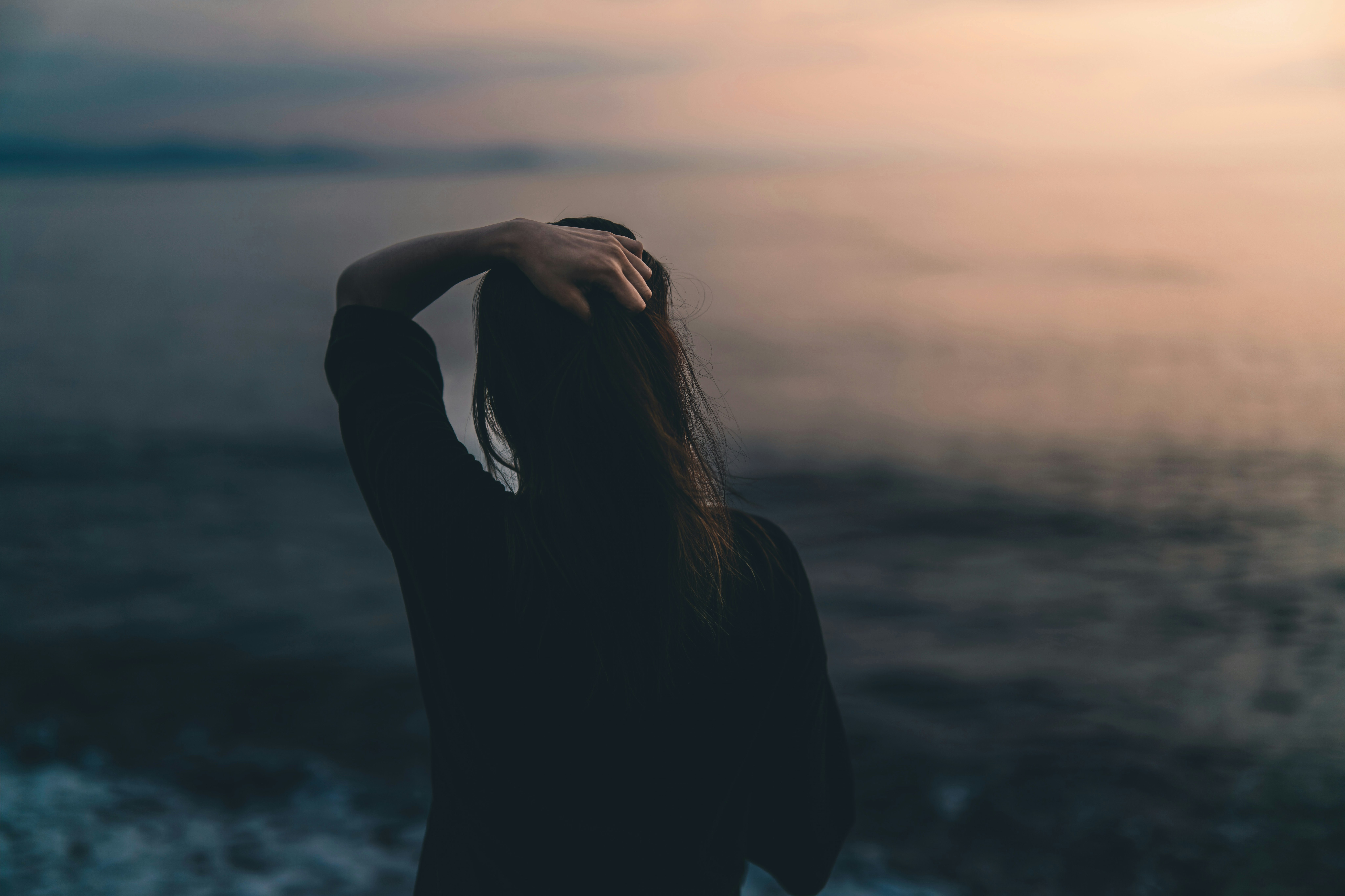 portrait of a person holding their hair by the seaside