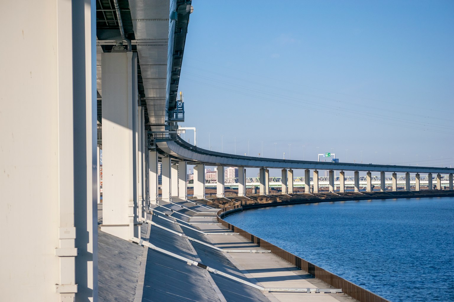 Curved bridge over water with shadows