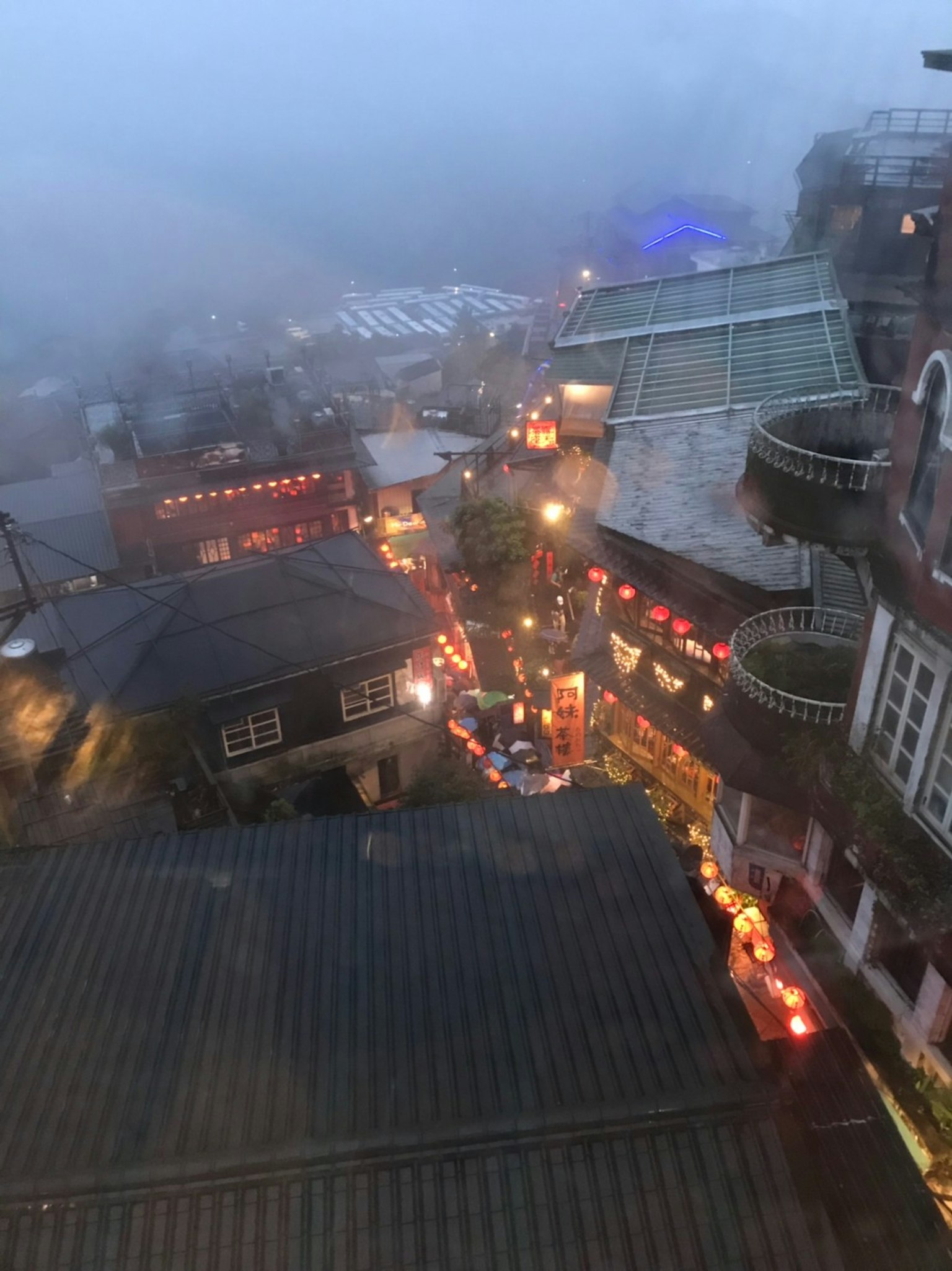 Foggy night view of a street with lanterns and small shops