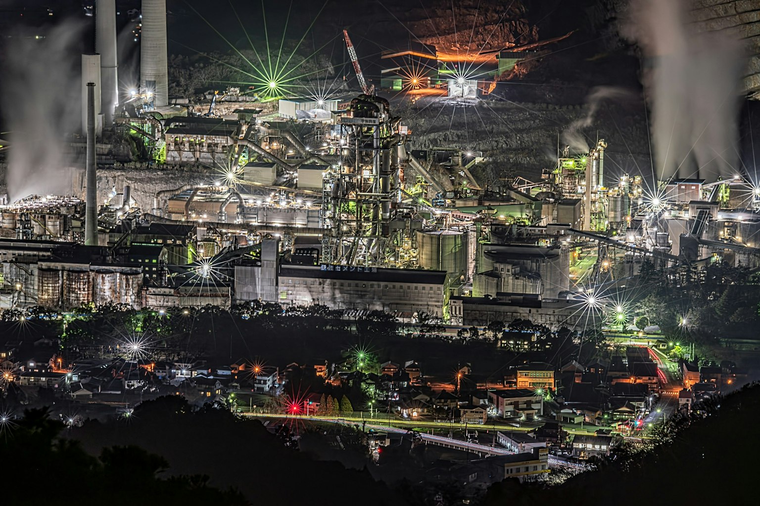 Vista nocturna de una instalación industrial con luces brillantes y vapor
