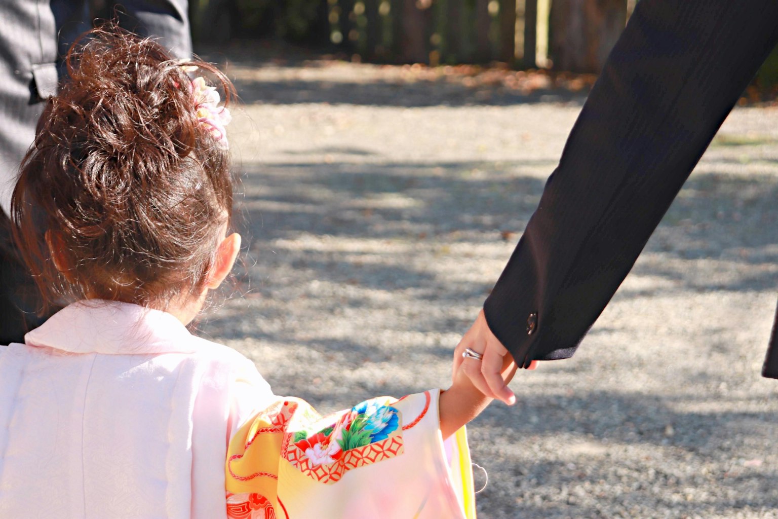 Un bambino in un kimono colorato che tiene la mano di un adulto all'aperto