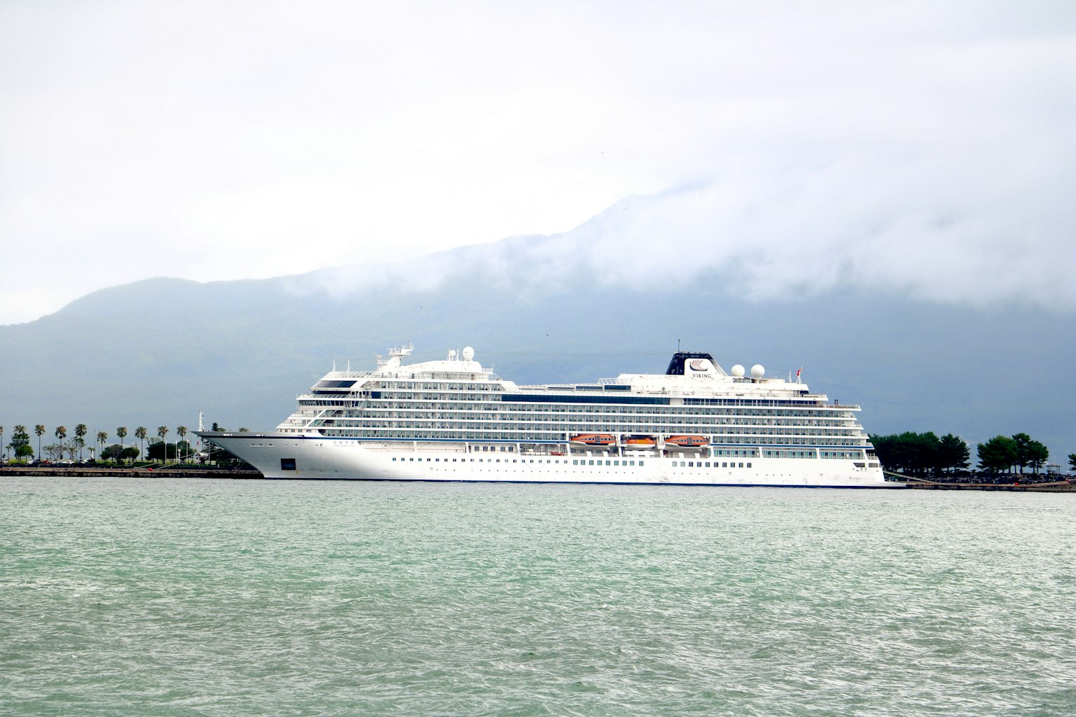 Un gran crucero atracado en un puerto con montañas al fondo
