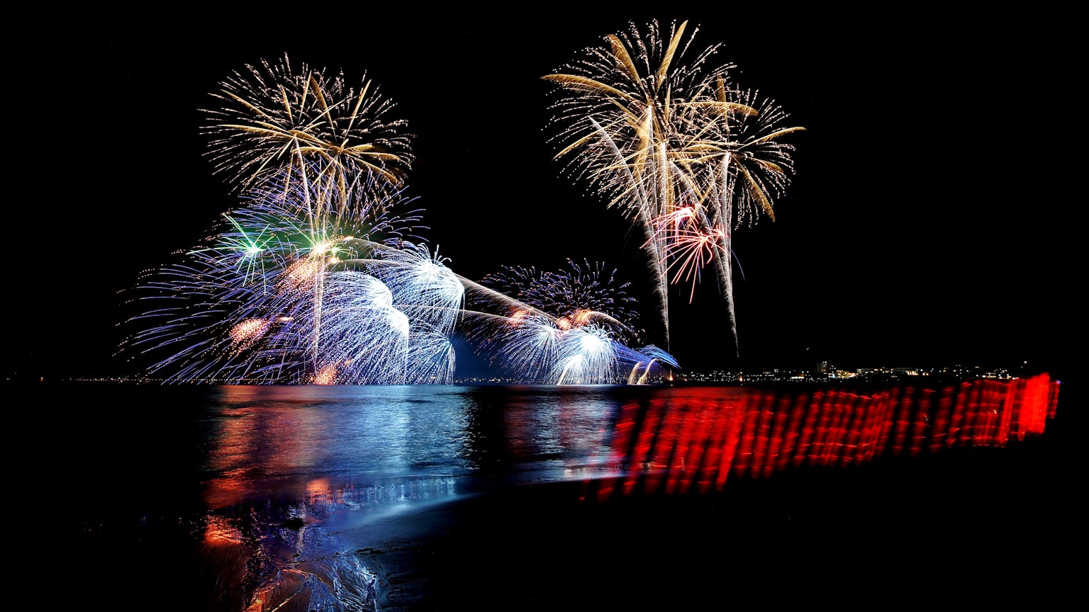 五彩缤纷的烟花照亮夜空，水面上有倒影