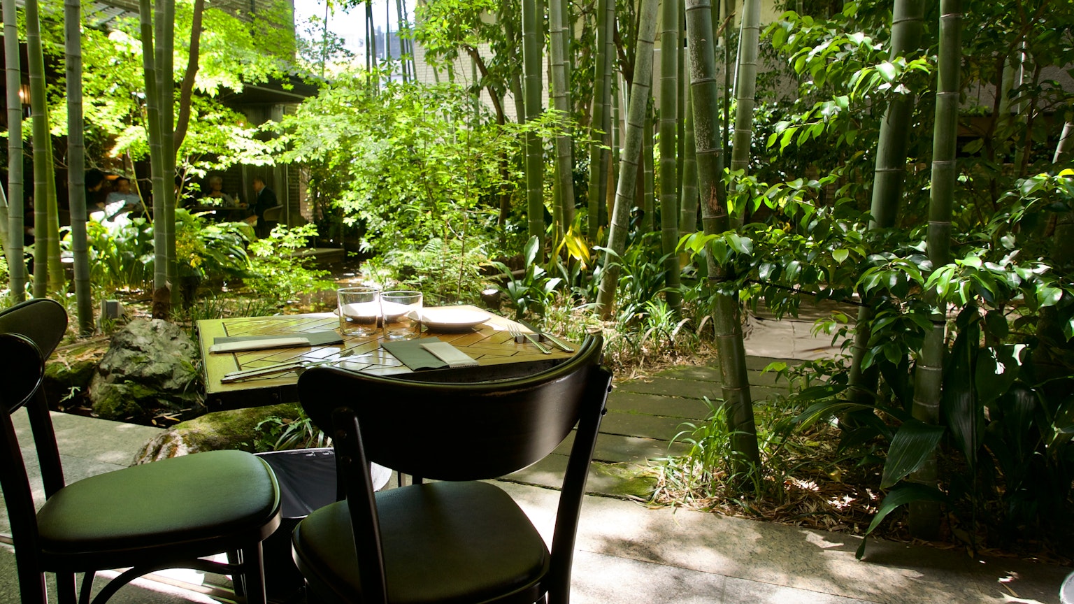 Un tavolo e sedie da giardino sereni circondati da bambù