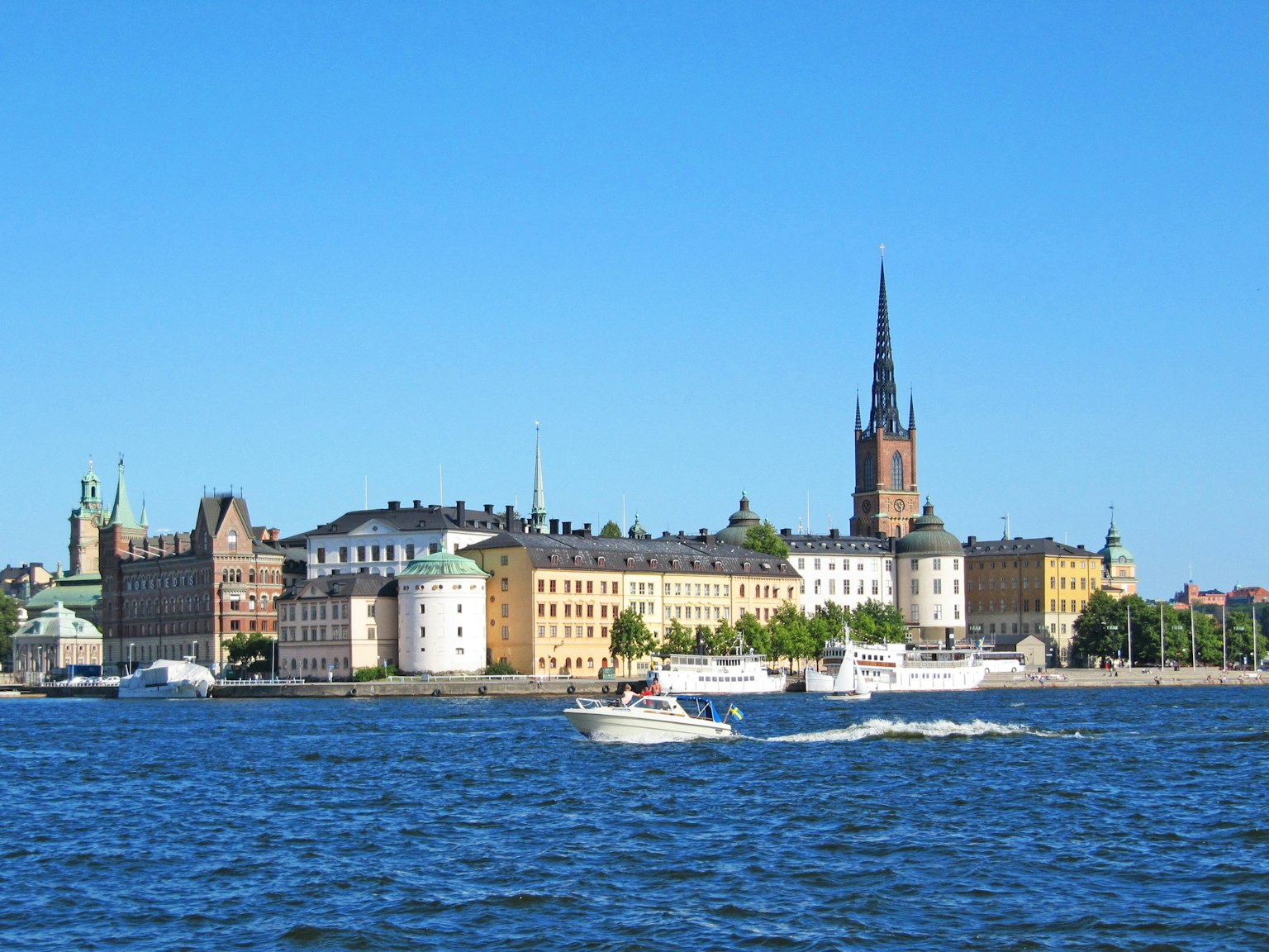 Boats on the water with the historic buildings of Stockholm in the background