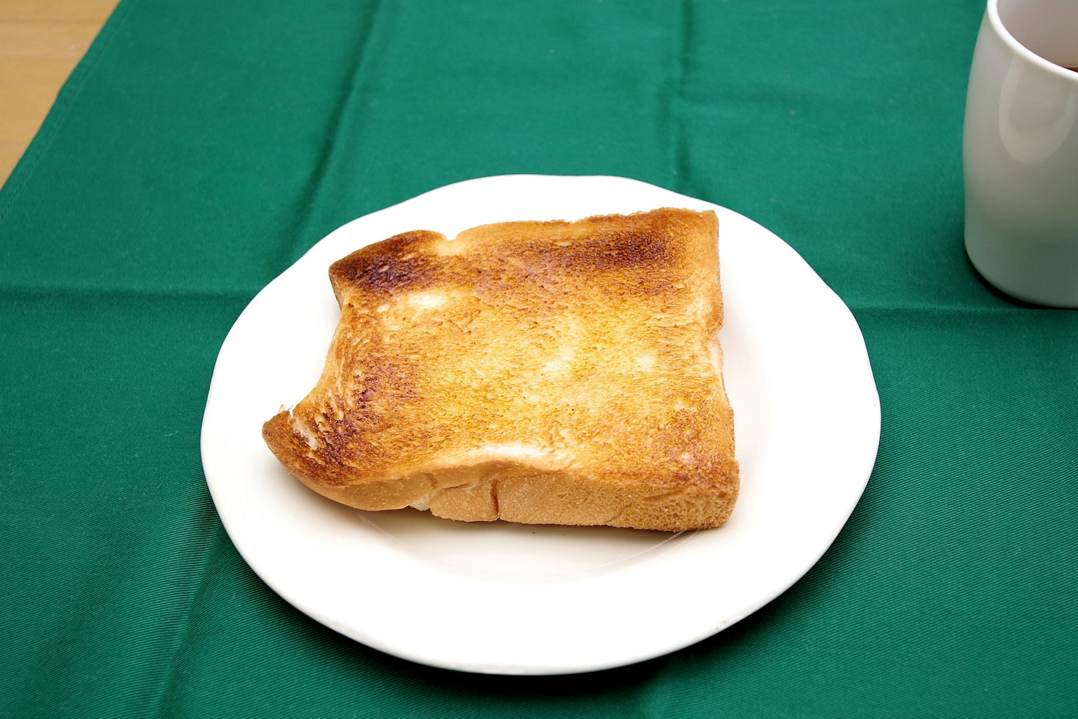 Bánh mì nướng vàng trên đĩa trắng với khăn trải bàn màu xanh