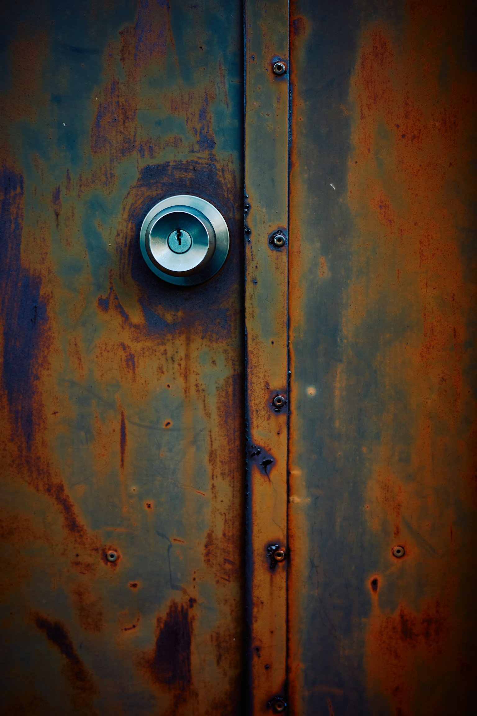 Close-up image of a rusty metal door featuring a keyhole
