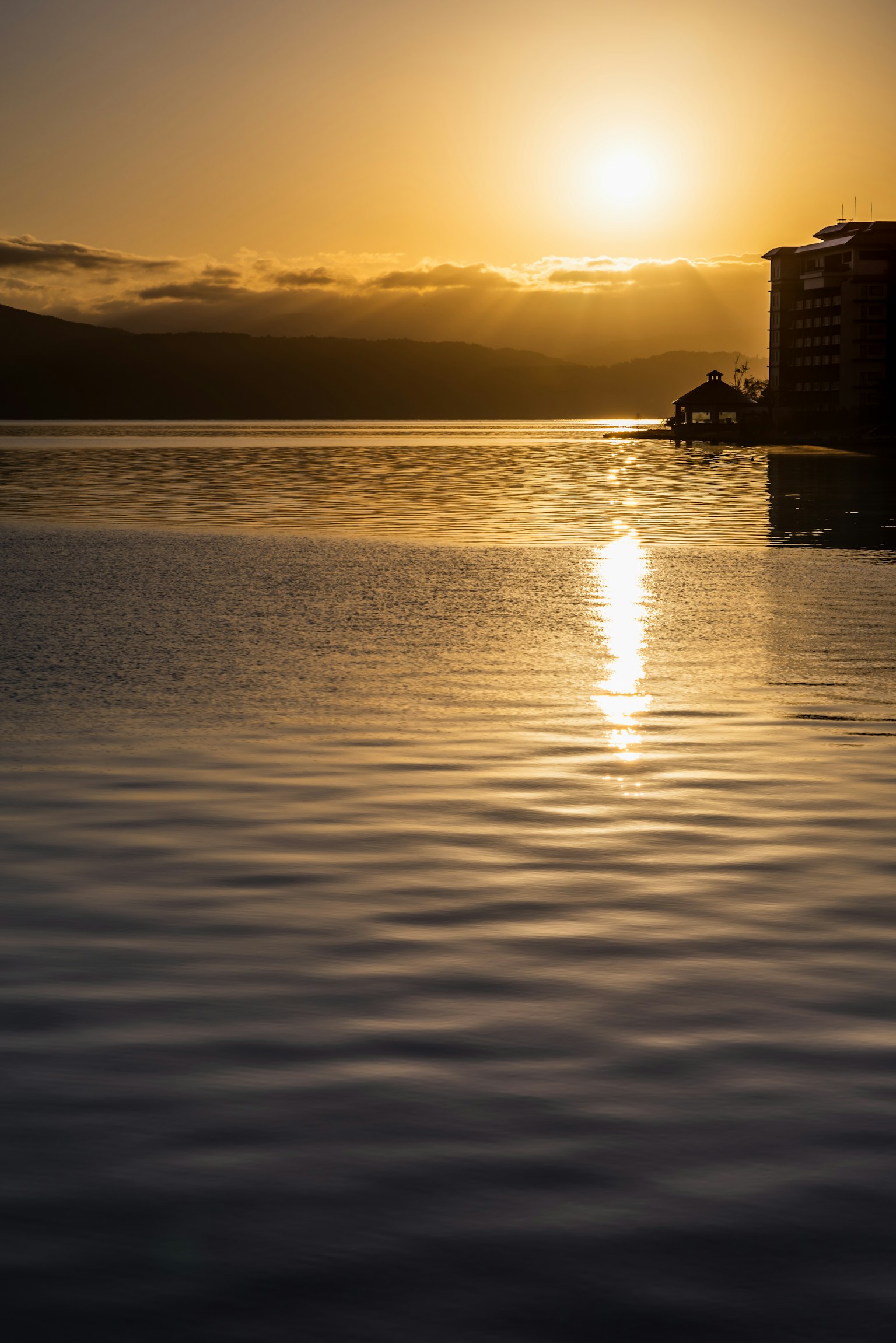 Scena di lago tranquillo con il sole che tramonta che si riflette sull'acqua