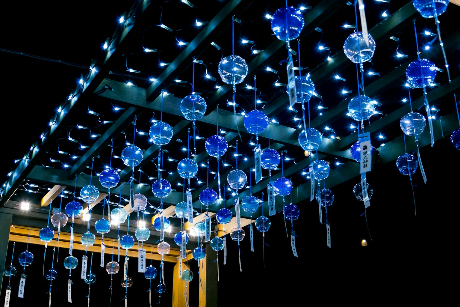 Una escena nocturna con campanas de viento azules colgadas iluminadas por luces mágicas