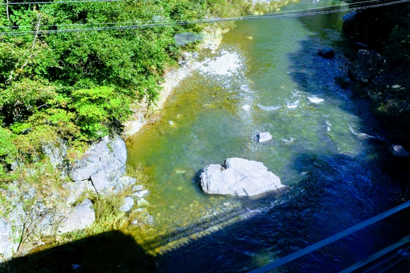 river water with white rocks and lush greenery along the bank