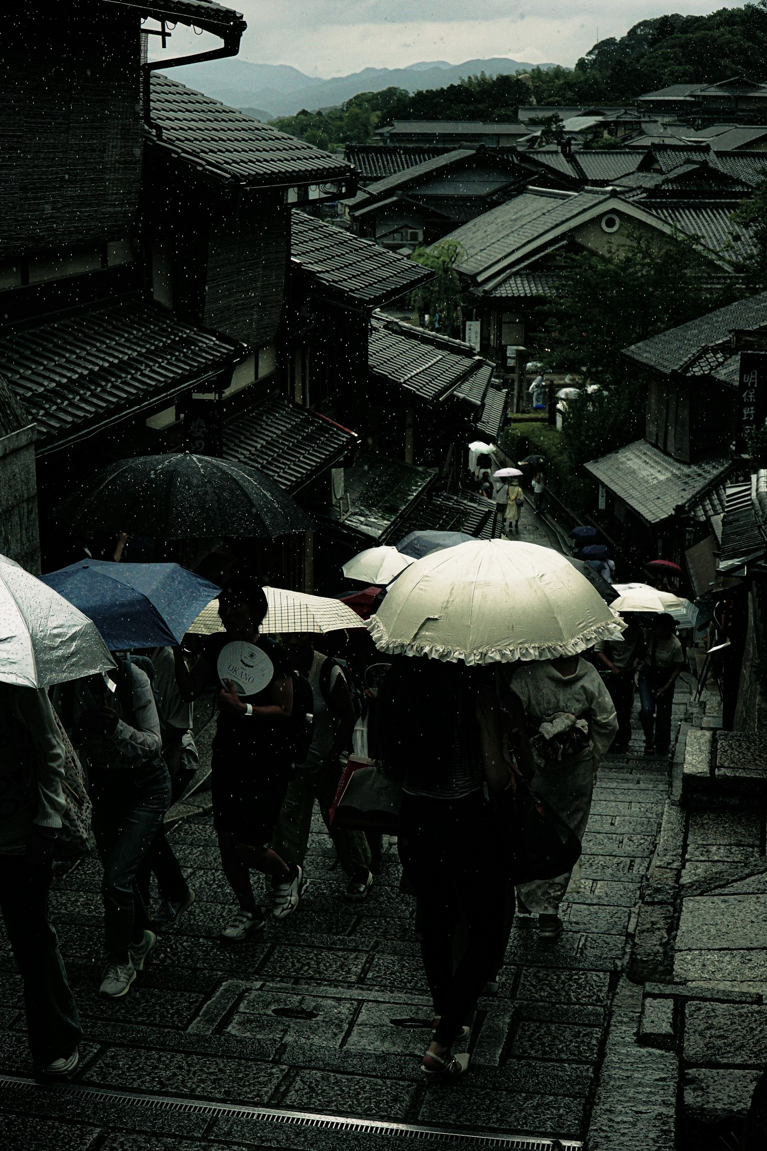 Người đi bộ dưới mưa với ô trên phố Kyoto