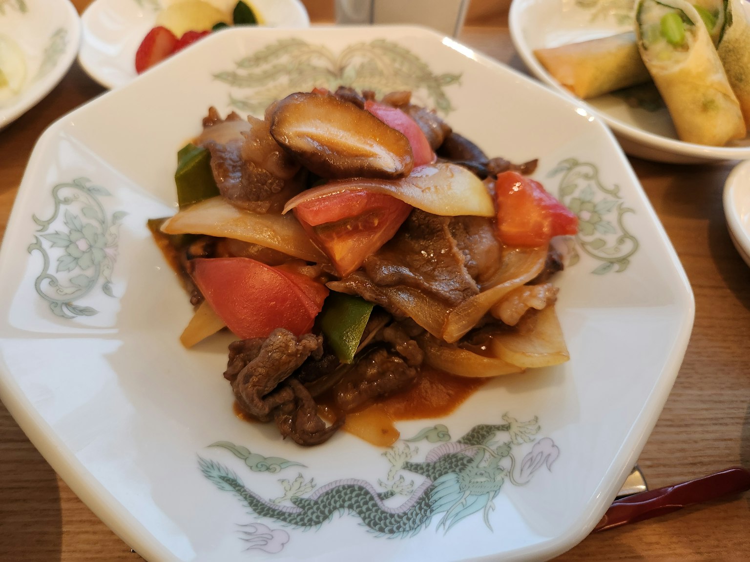 Un piatto colorato di carne e verdure servito su un piatto bianco con pomodori e peperoni
