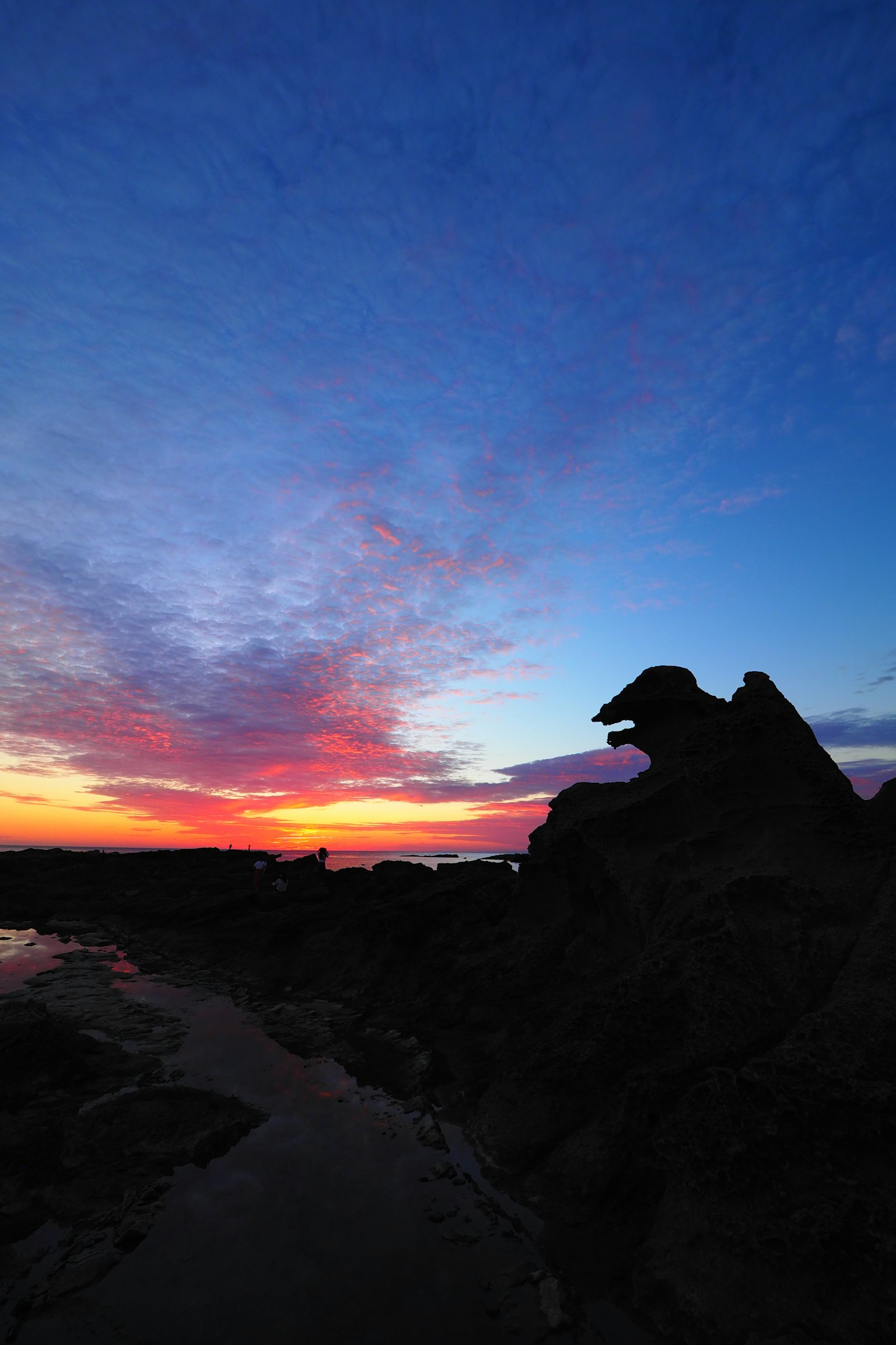 Langit senja dramatis dengan siluet formasi batu
