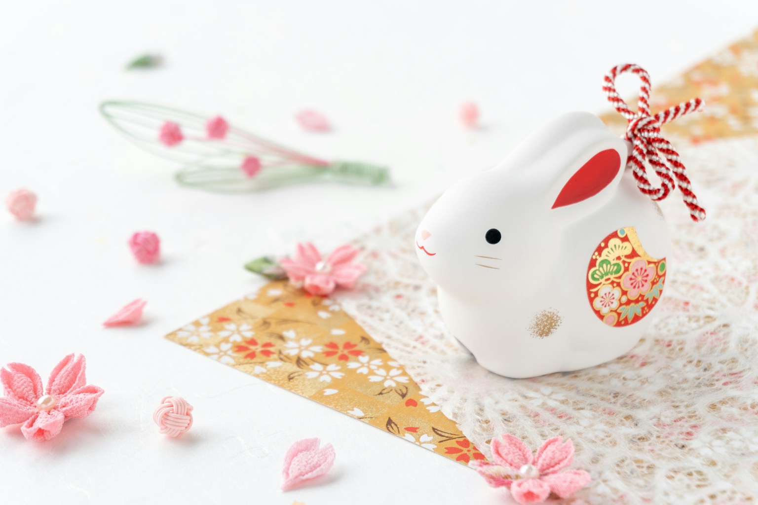 Una figurina di coniglio carina posizionata su un tessuto colorato con petali di fiori sparsi