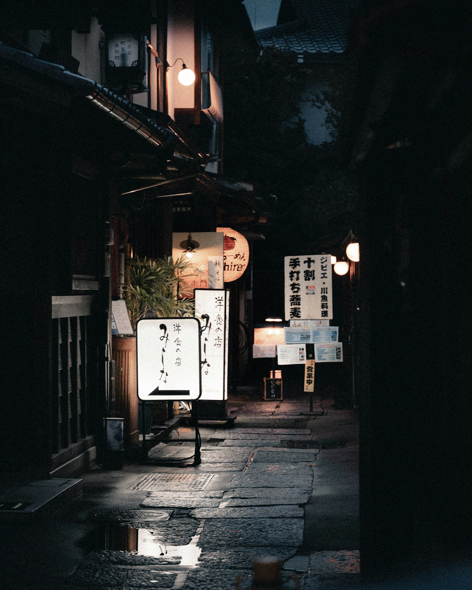 Eine enge Gasse bei Nacht, beleuchtet von sanften Lichtern und Schildern