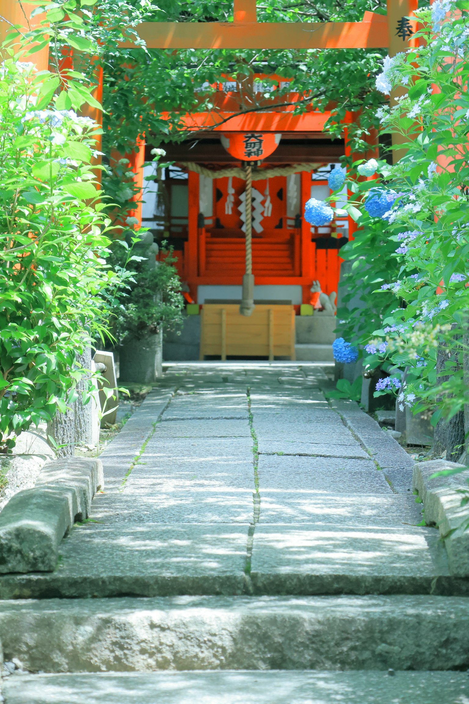 Camino de piedra que lleva a un santuario naranja rodeado de vegetación