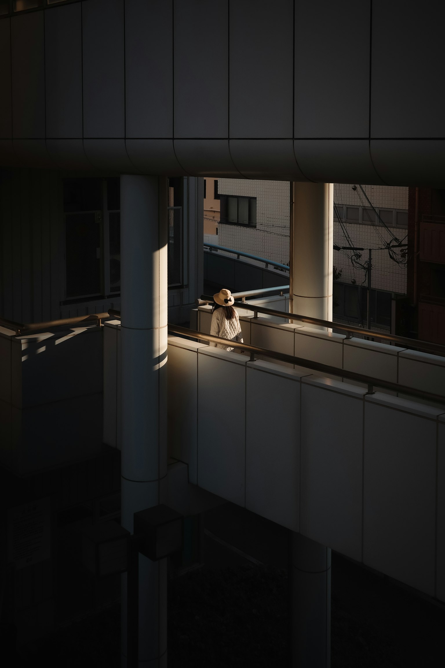Una persona iluminada por la luz en una estructura arquitectónica moderna con sombras
