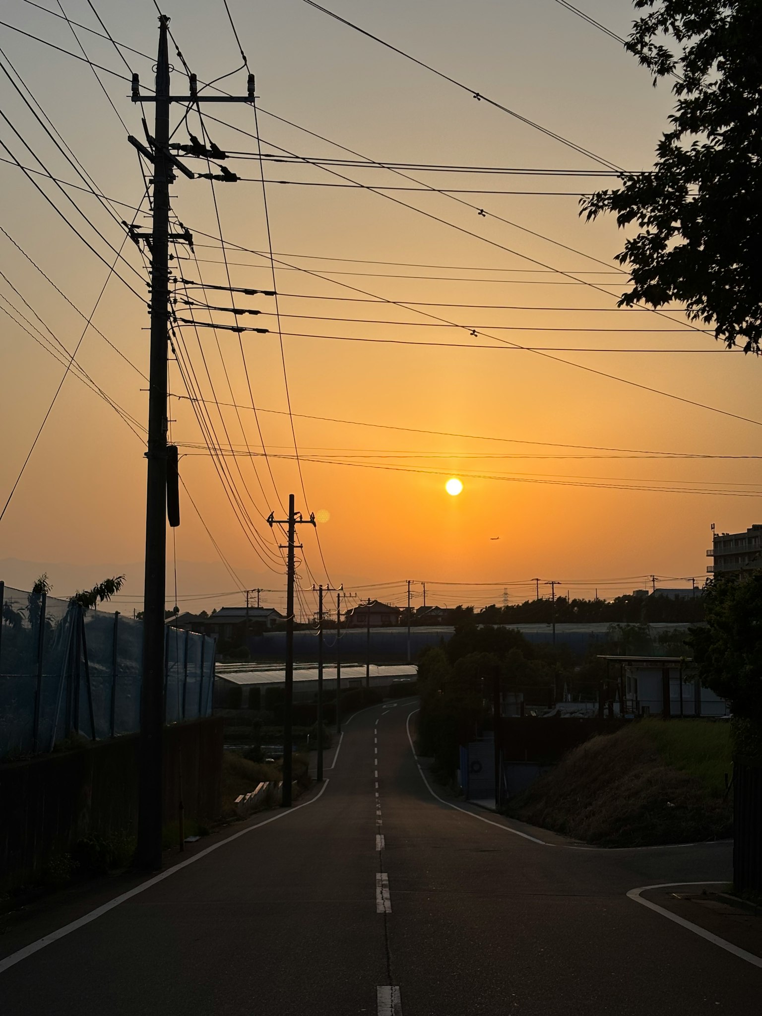 Vista escénica de una carretera al atardecer con líneas eléctricas y un cielo vibrante