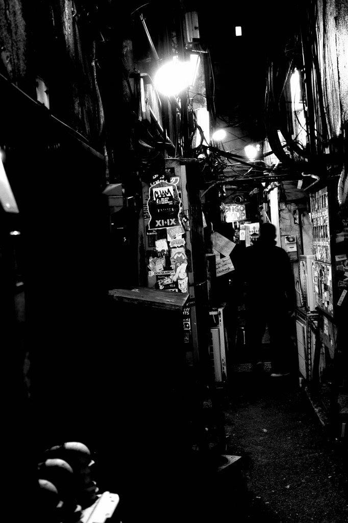 ruelle nocturne avec enseignes et silhouettes