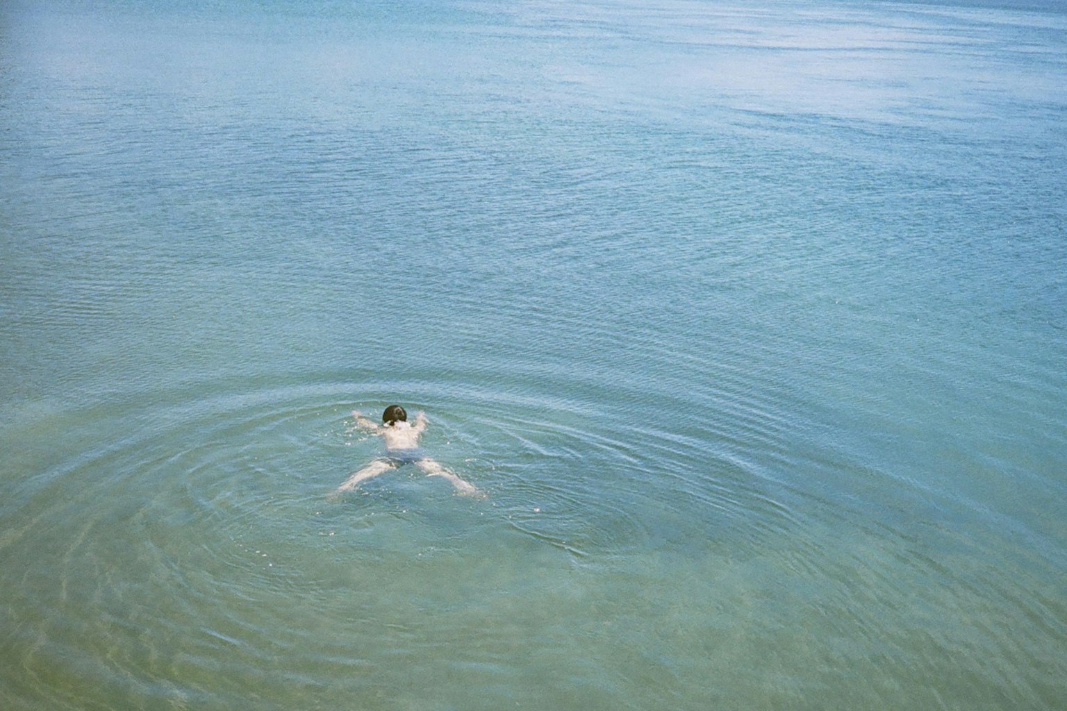 Une personne nageant dans une eau claire vue d'en haut des ondulations se propageant à la surface