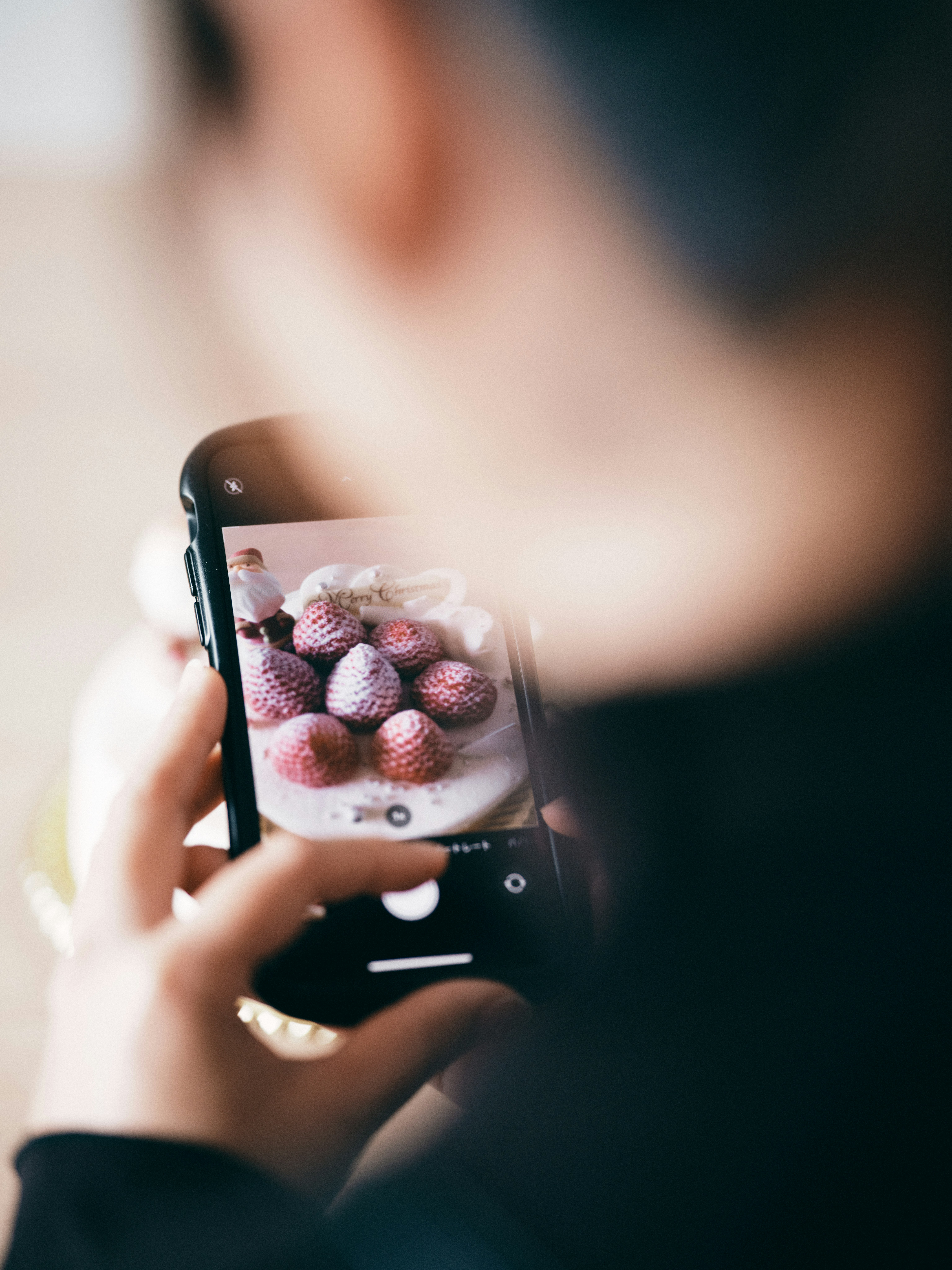 A woman taking a photo of colorful pastries with her smartphone