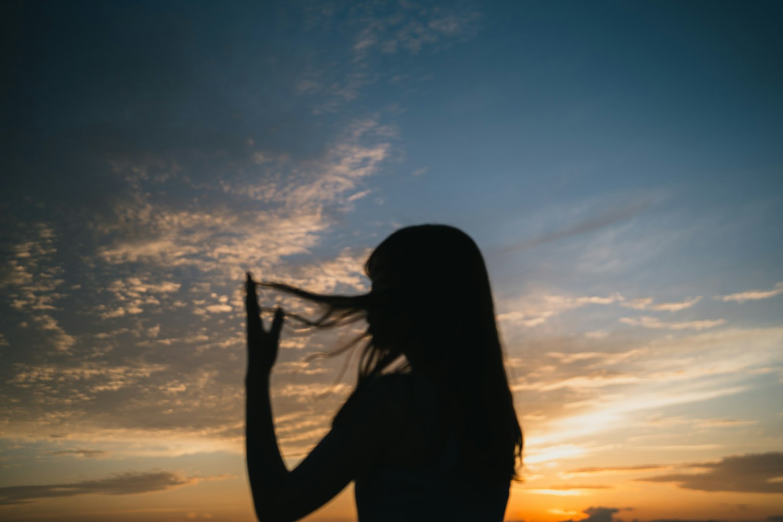 夕陽下的女性剪影在玩弄頭髮