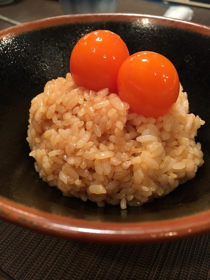 オレンジの卵黄がのった茶碗の焼き飯