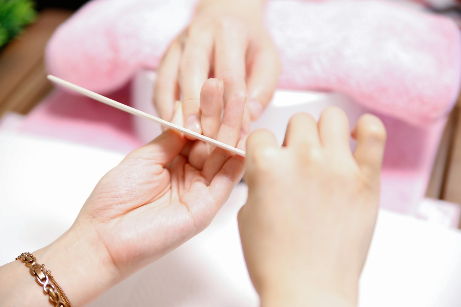 Hai bàn tay tham gia vào quá trình chăm sóc móng cầm một que gỗ